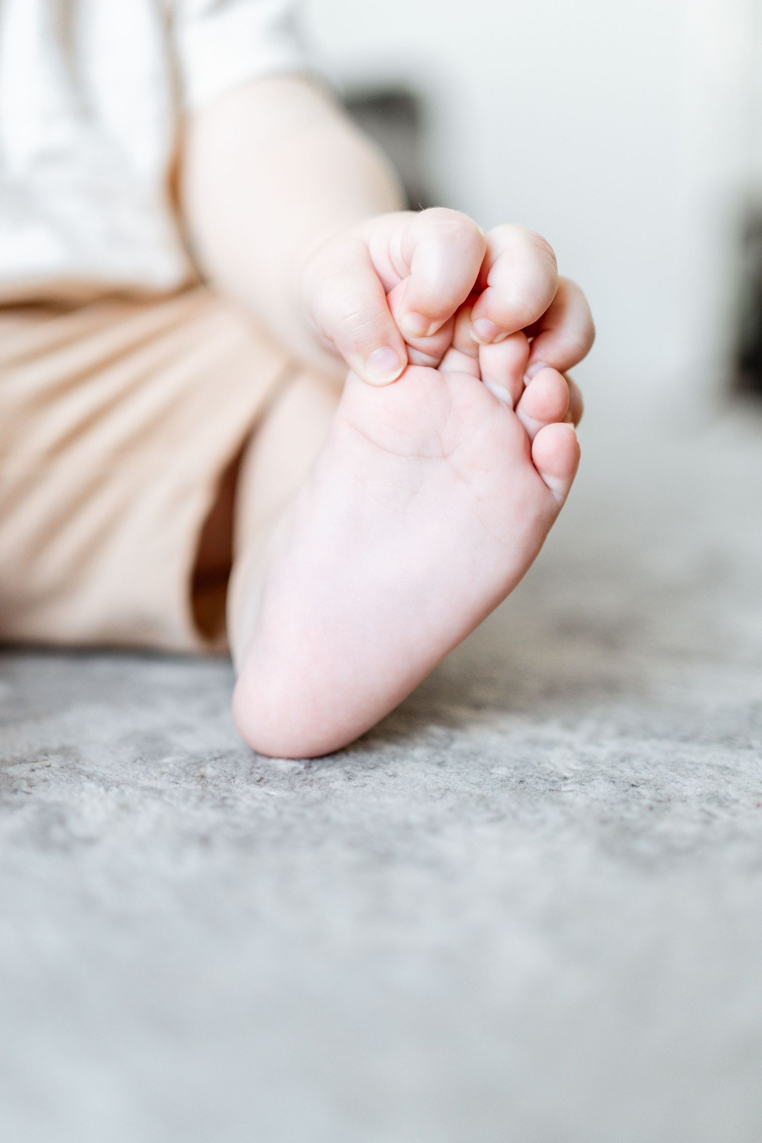 Close-up series of tiny baby feet on soft gray surface showing different angles and details.
