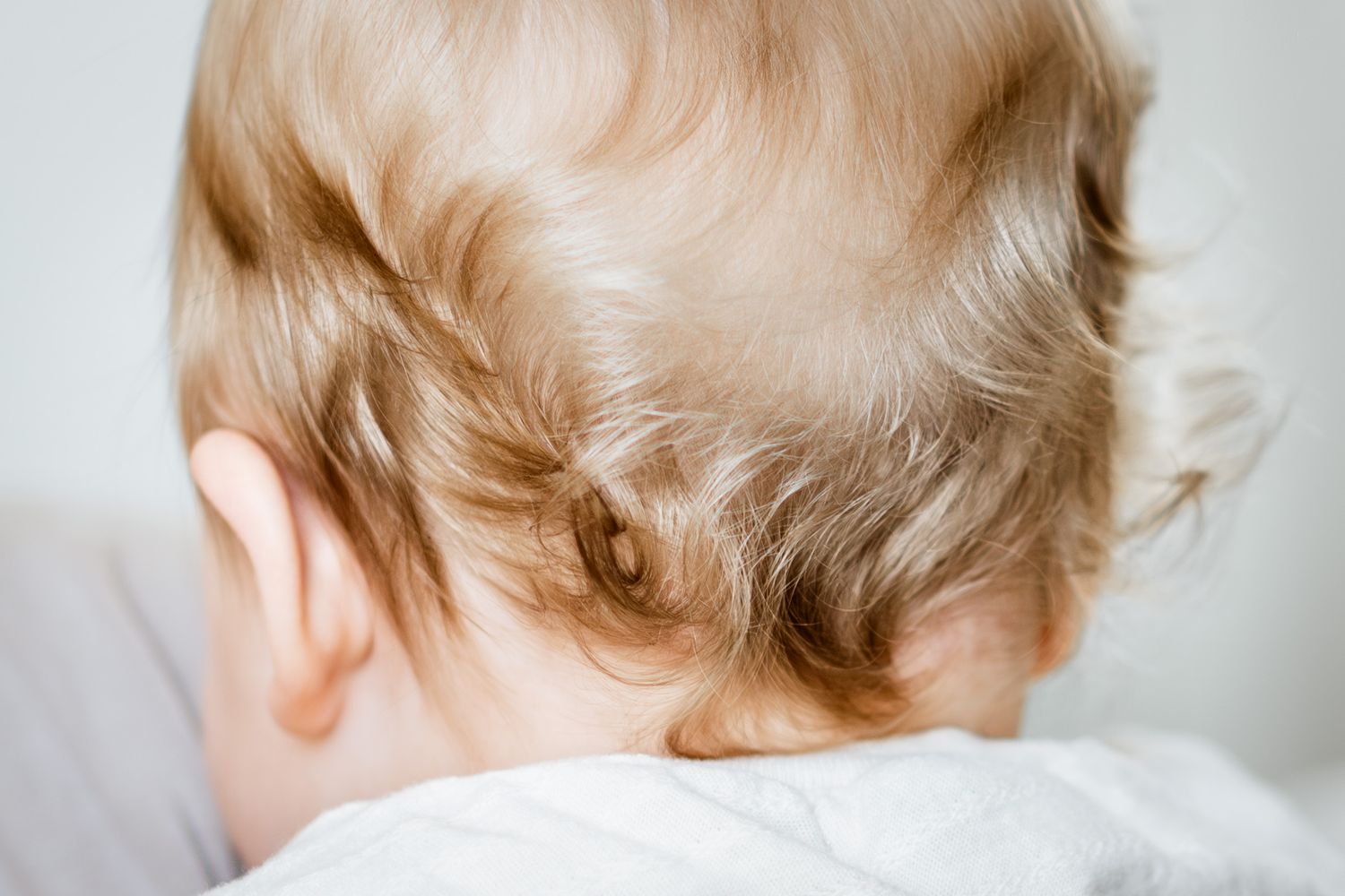 Close-up view of soft blonde curly hair against a light background.