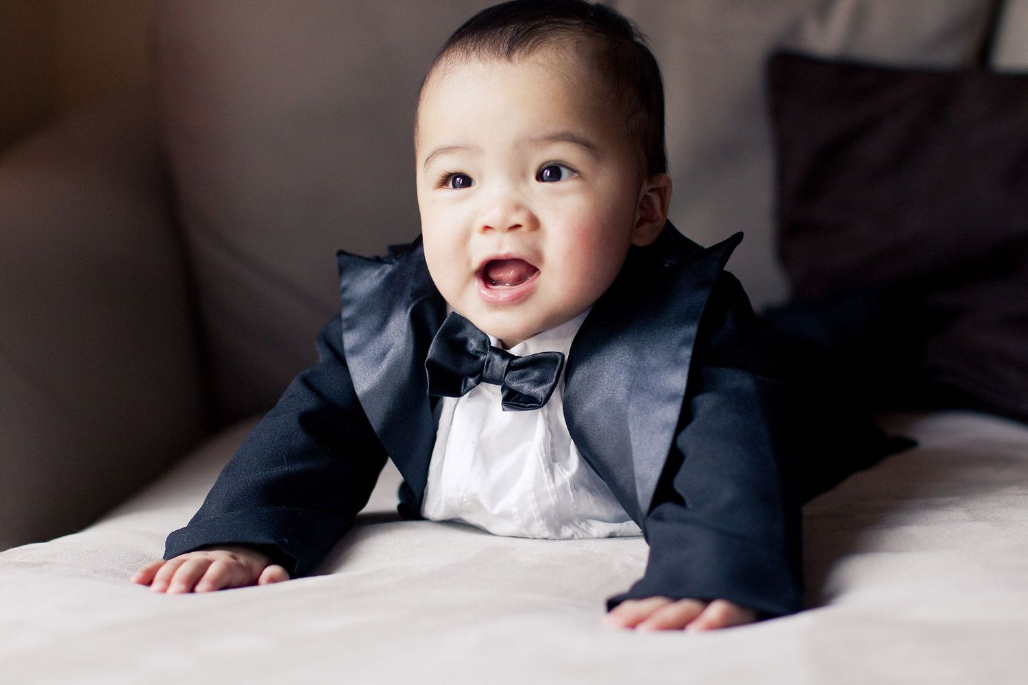 Baby in formal wear shown in series of black and white portraits.