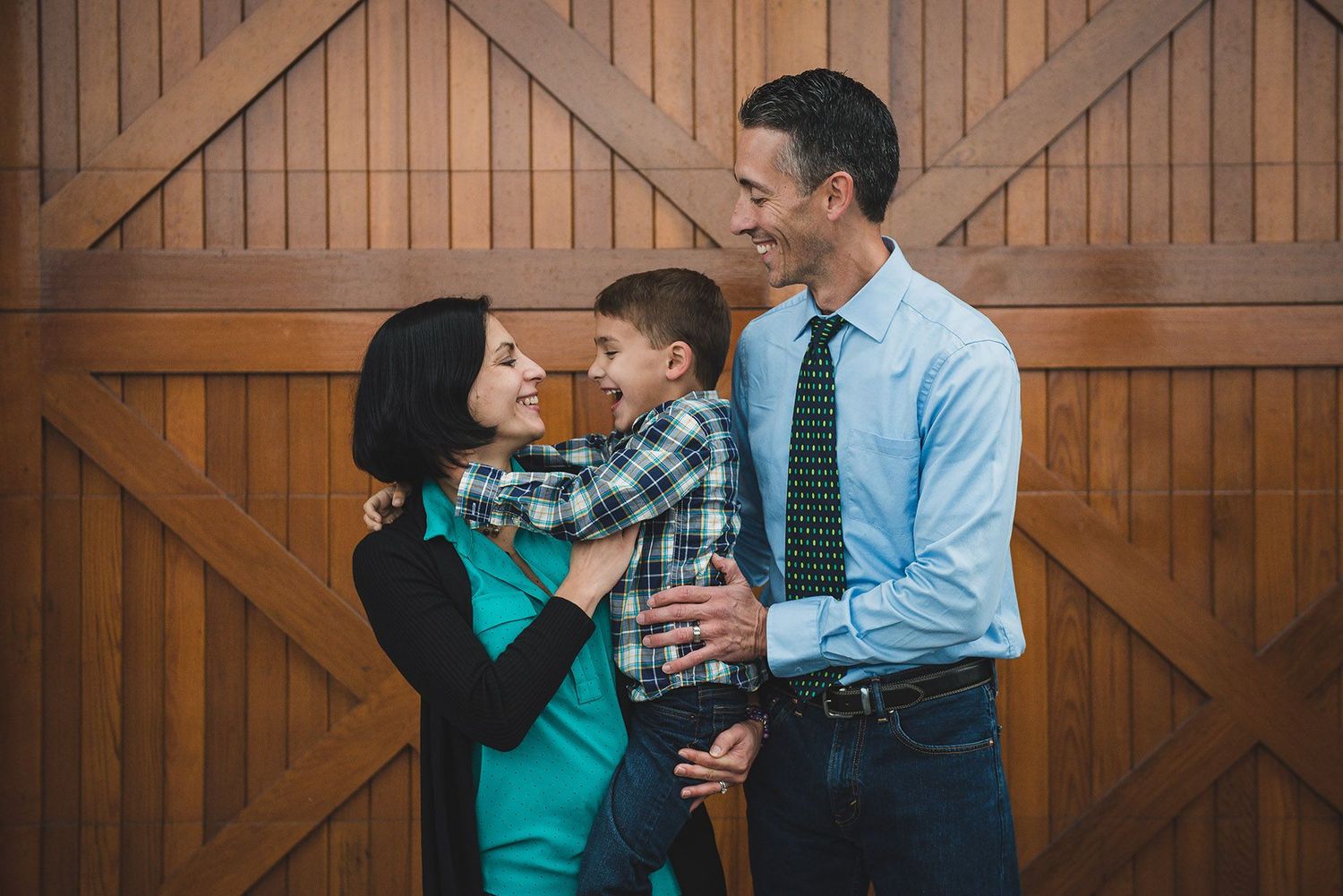 Family photo sequence in front of wooden barn doors showing playful interactions.