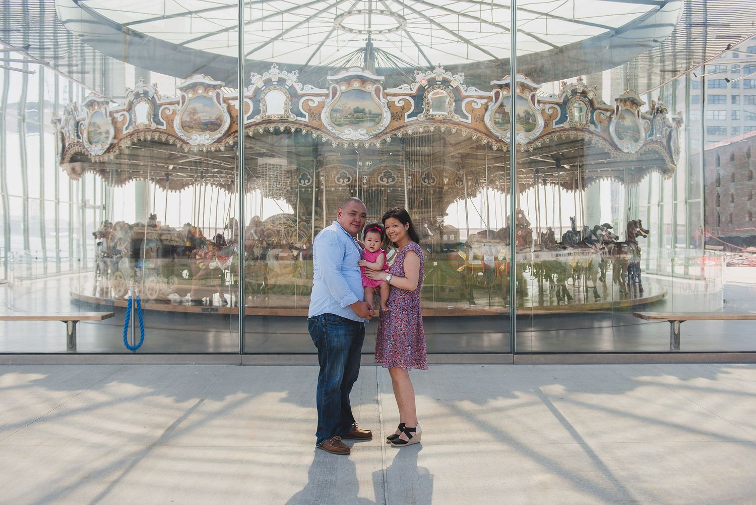 Vintage carousel with ornate decorations in glass-enclosed building.