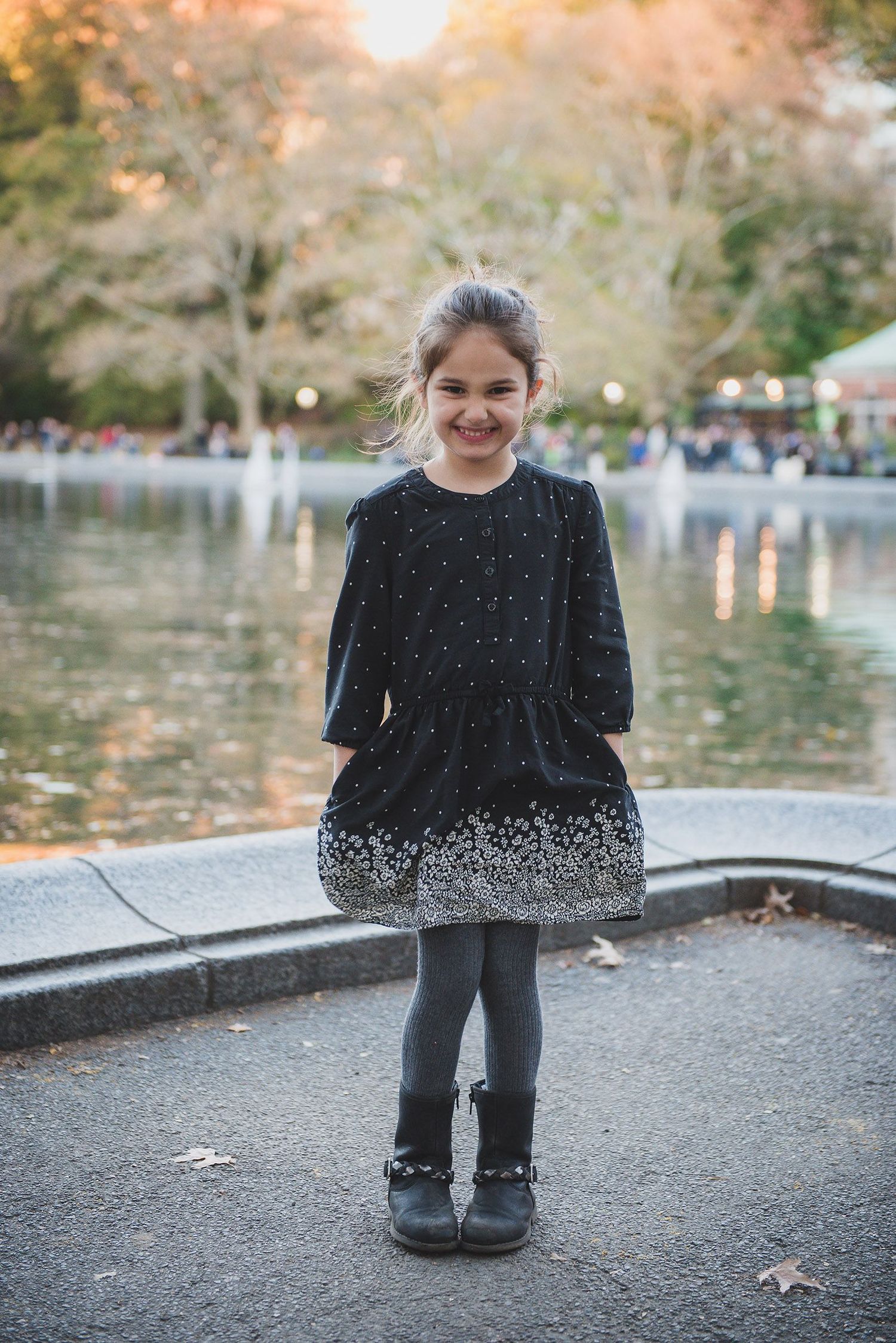Child in sparkly black dress poses on path during autumn.