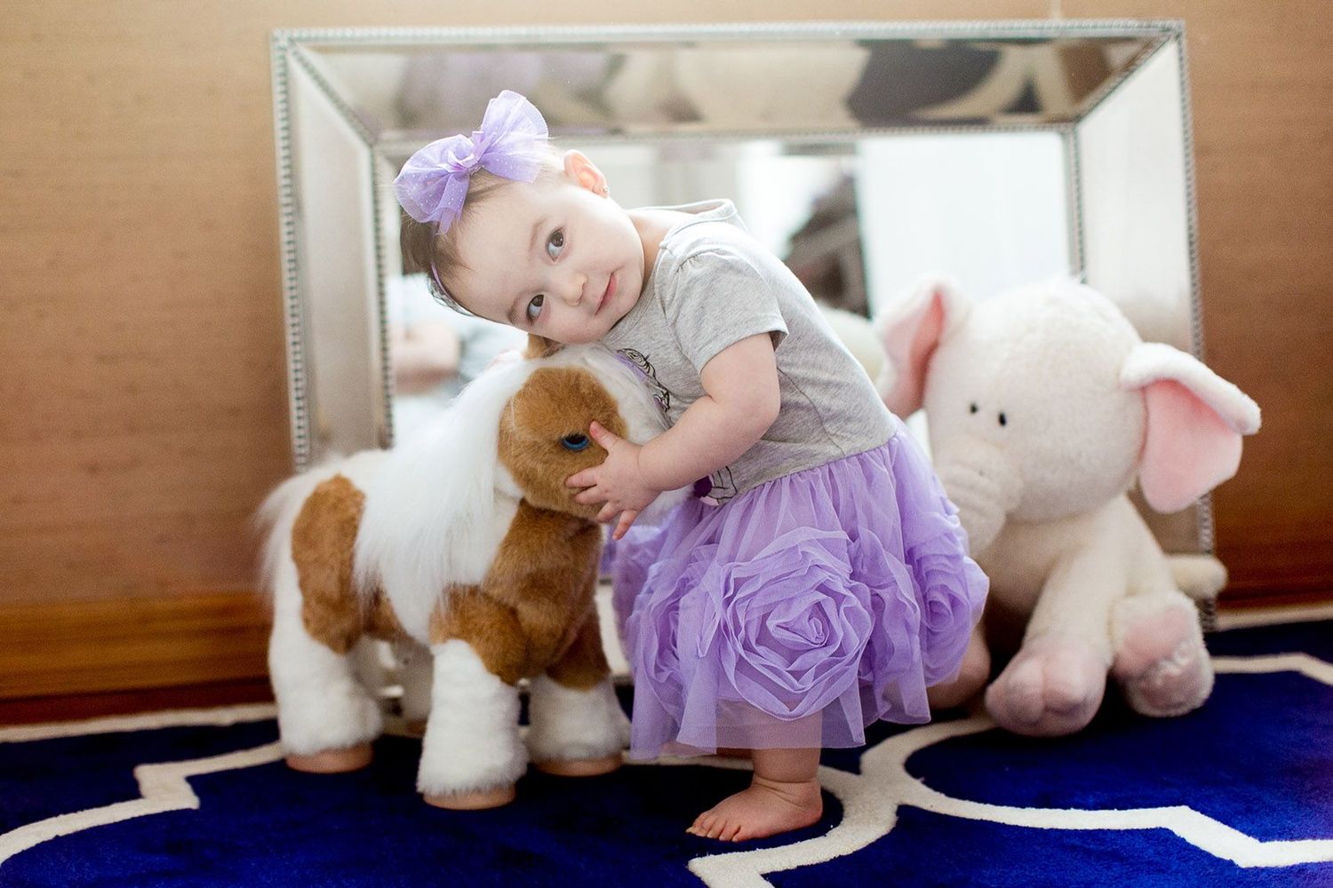 Baby playing with stuffed animals on blue carpet in sequential photos.