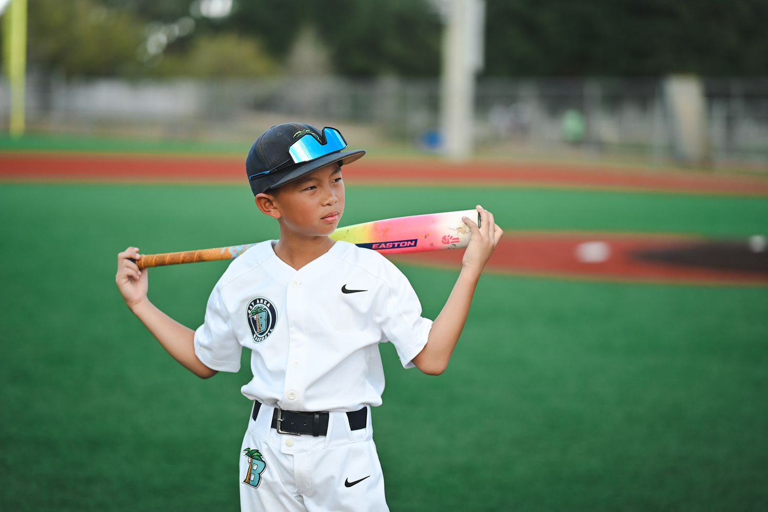 Young baseball players practicing on green field with equipment.