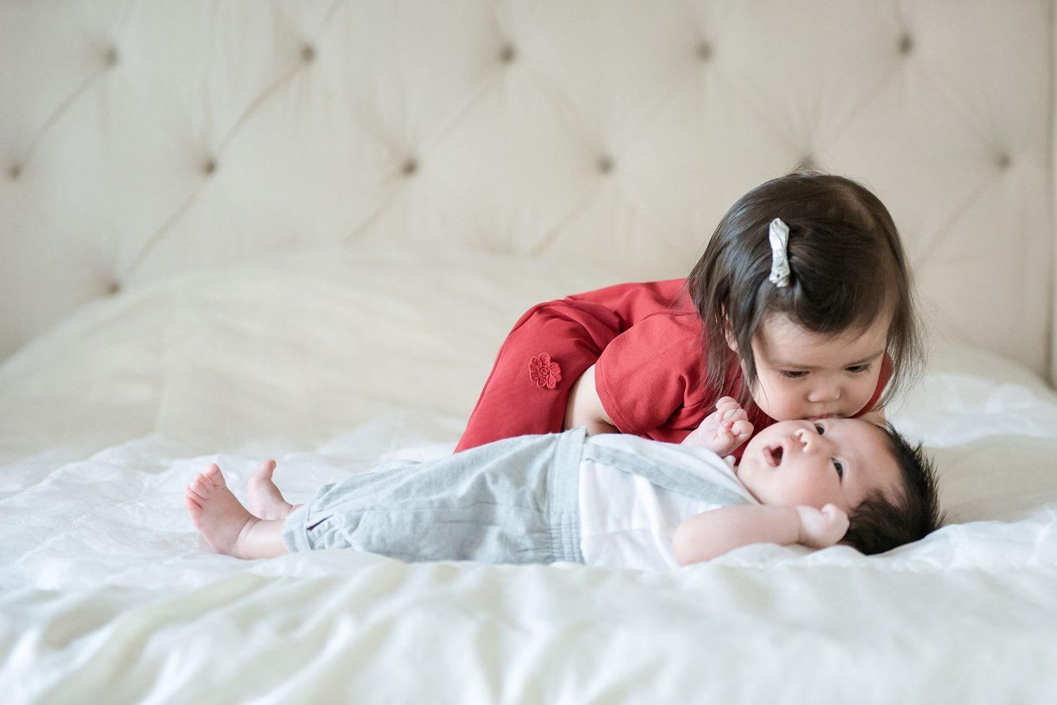 Young child rests peacefully on white tufted bedding.