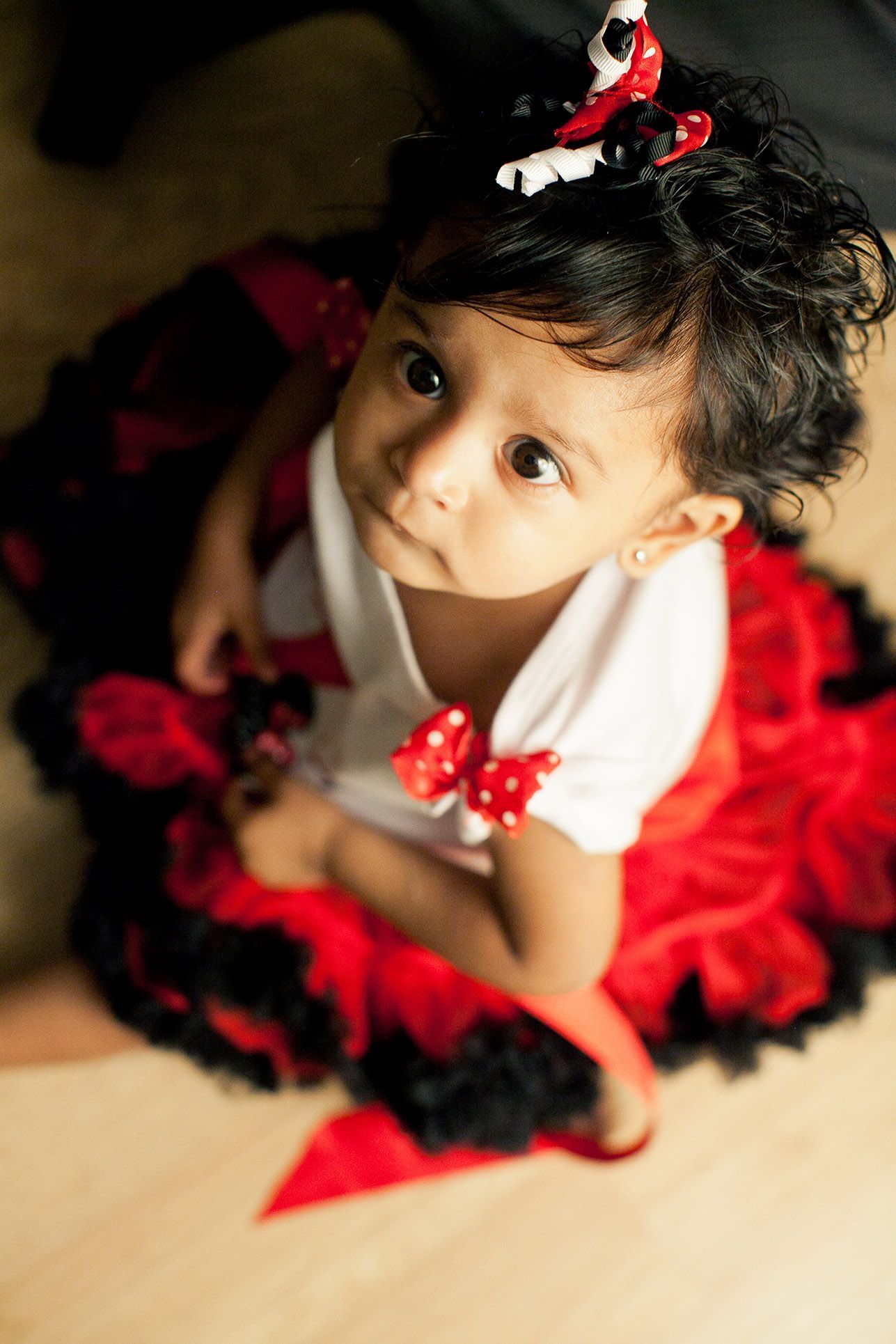 Overhead view of child in red and black tulle dress twirling against dark background.