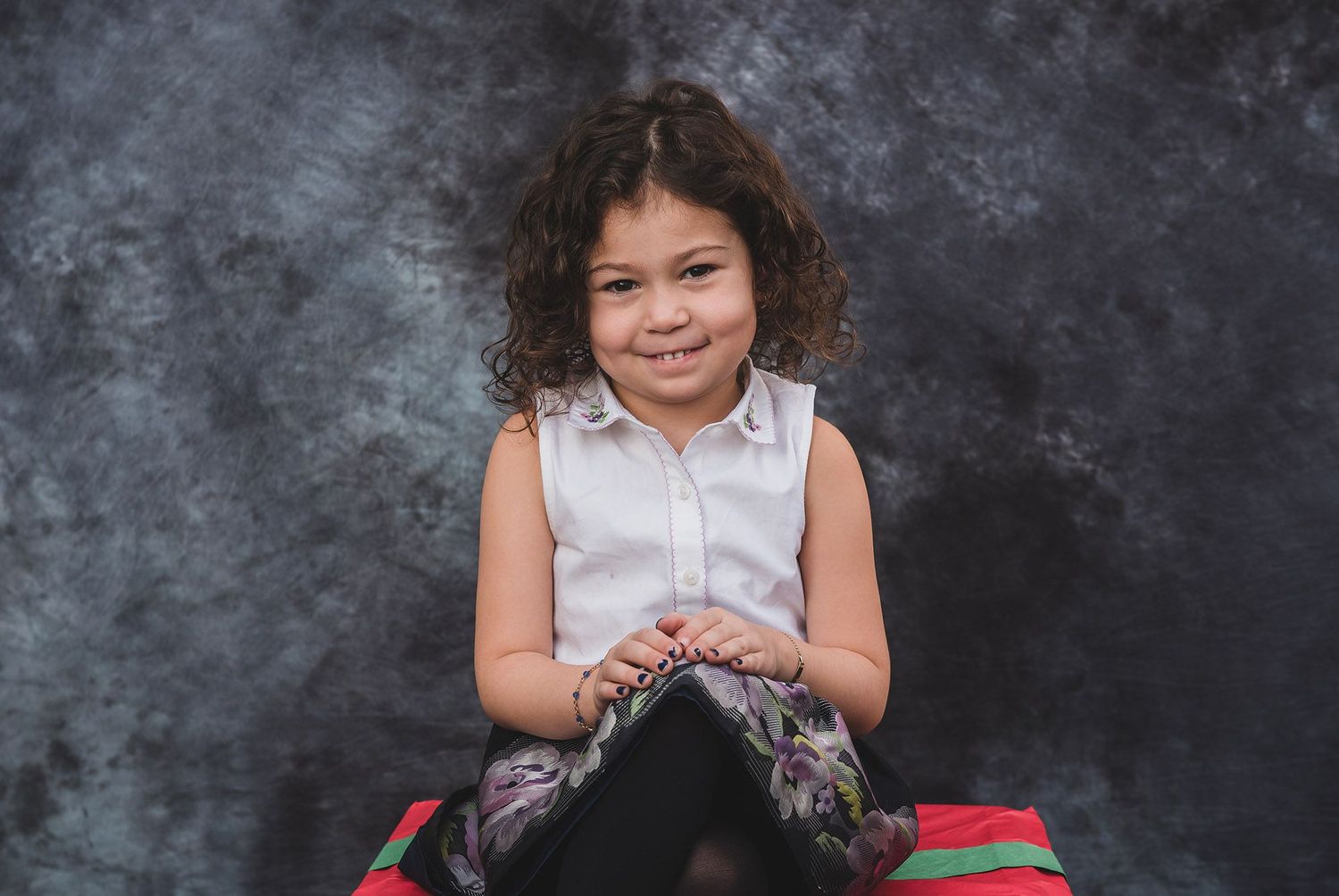 Studio portrait series against dark textured background with red dress accents.