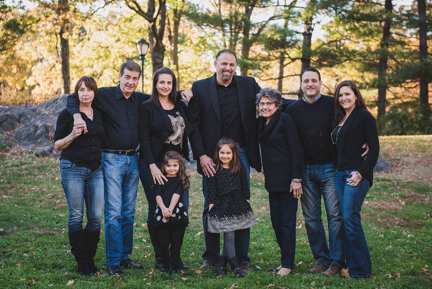 Extended family portrait session in an autumn park setting with fall foliage.
