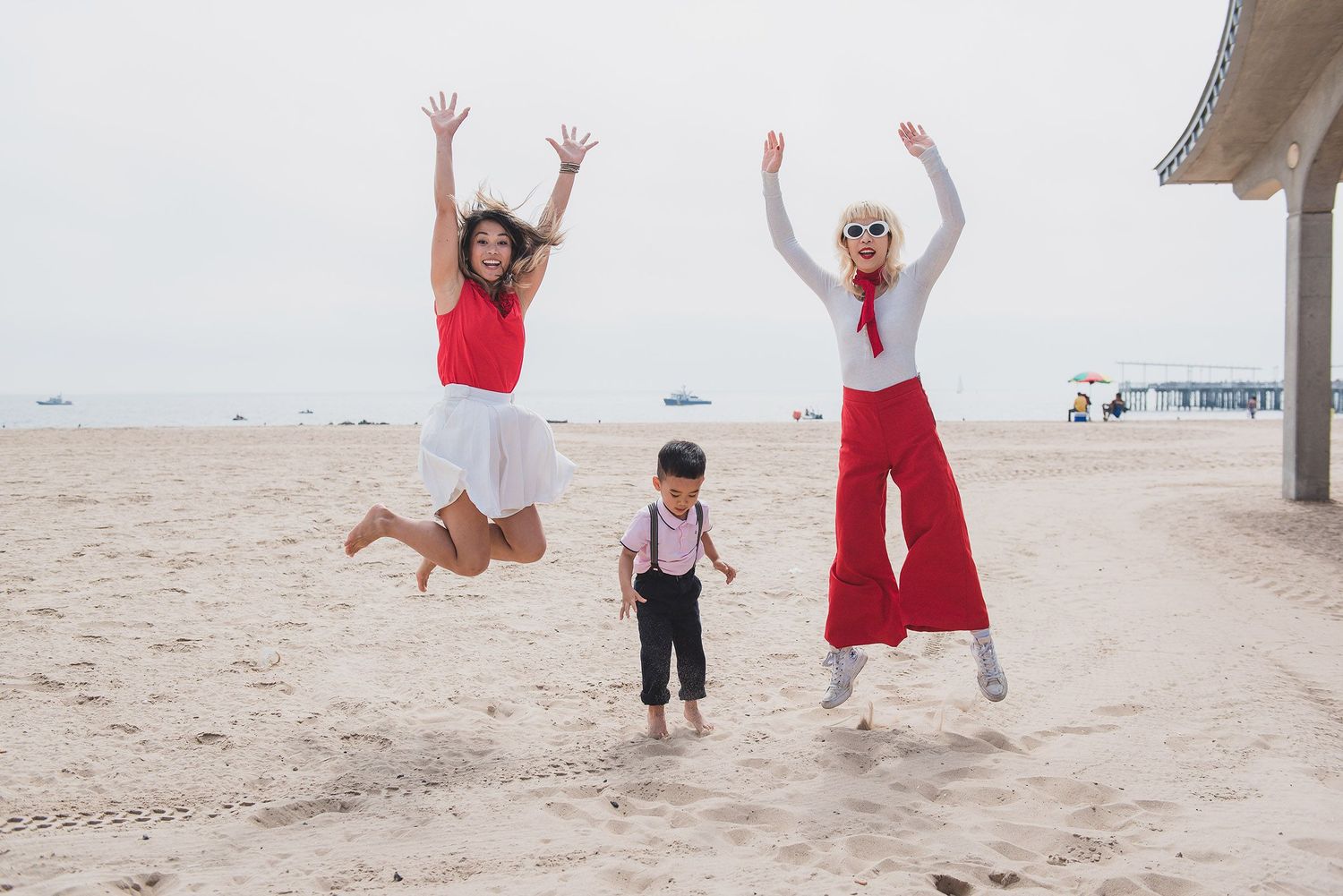 People jumping and playing together on sandy beach during sunset.