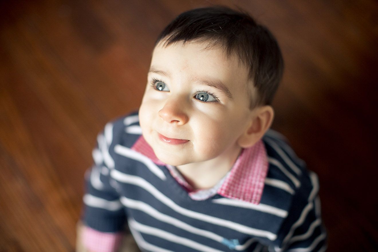 Young child in striped navy shirt looking up with soft lighting.