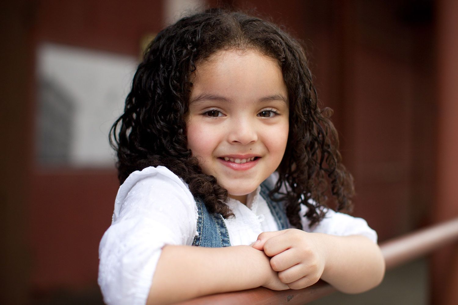 Candid outdoor portraits against rustic brick wall background.