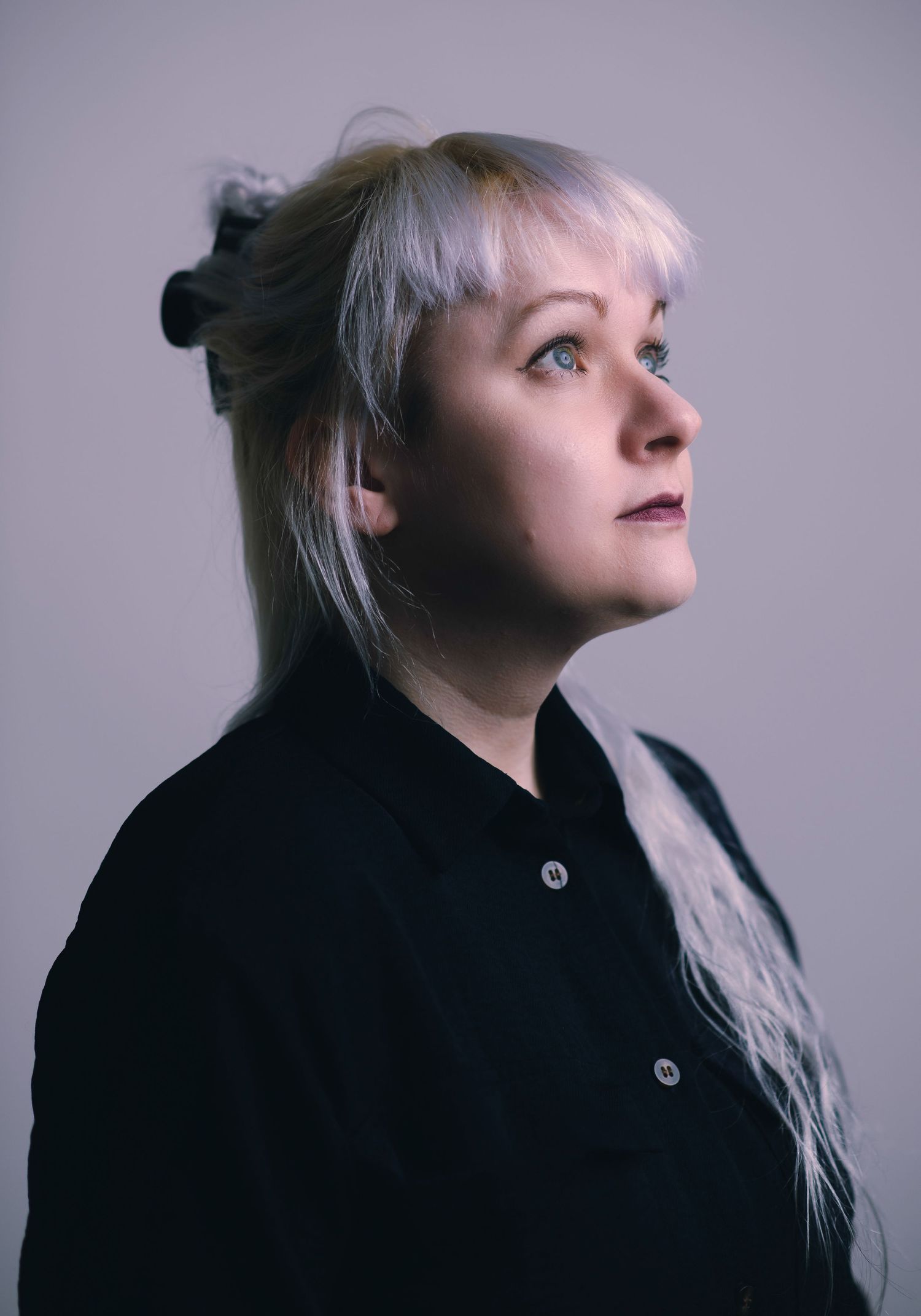 Glasgow corporate headshot of a woman in her thirties with white hair and a dark navy dress against a white background