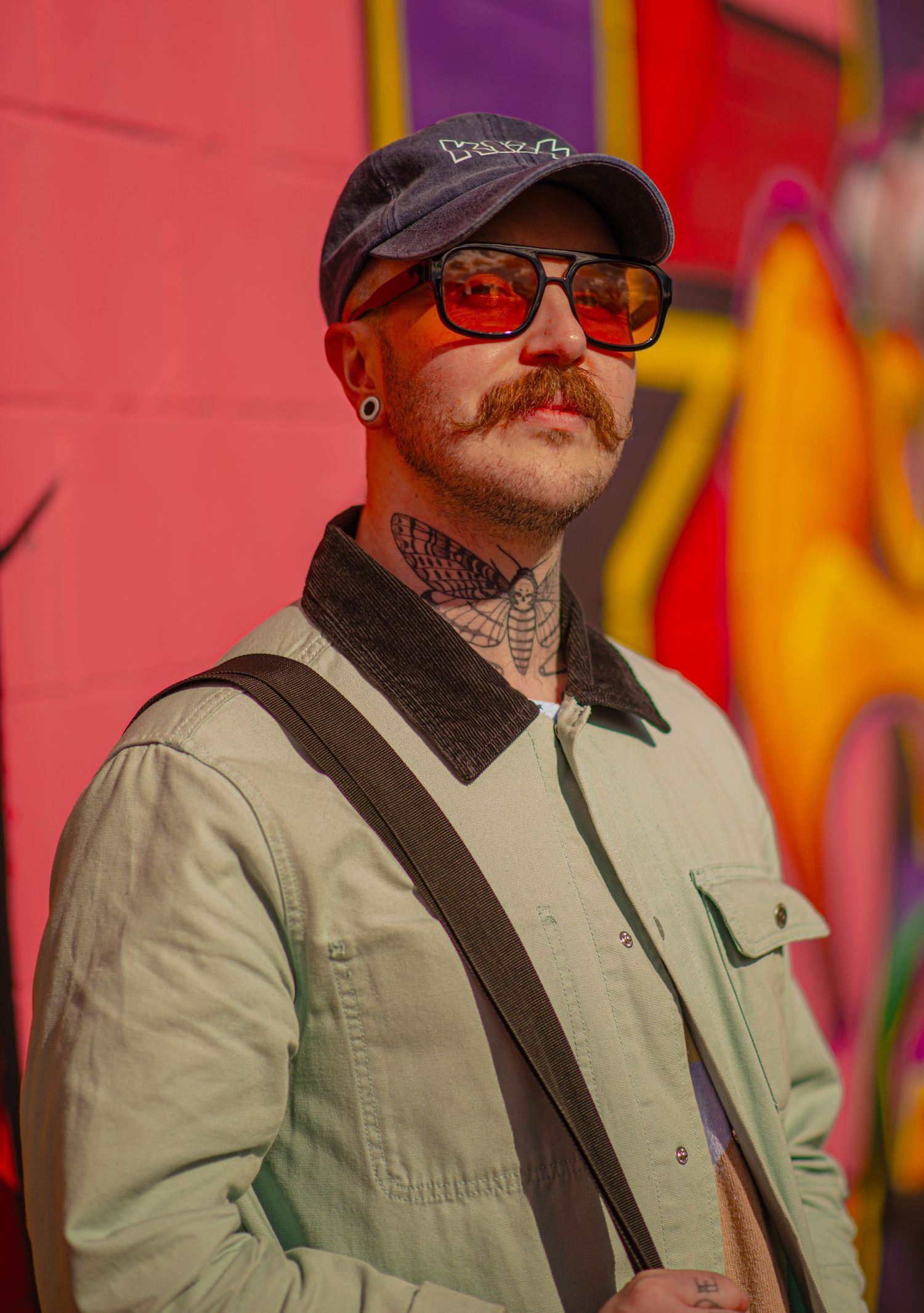 Glasgow creative portrait of a man in his thirties leaning on a wall of colourful graffiti