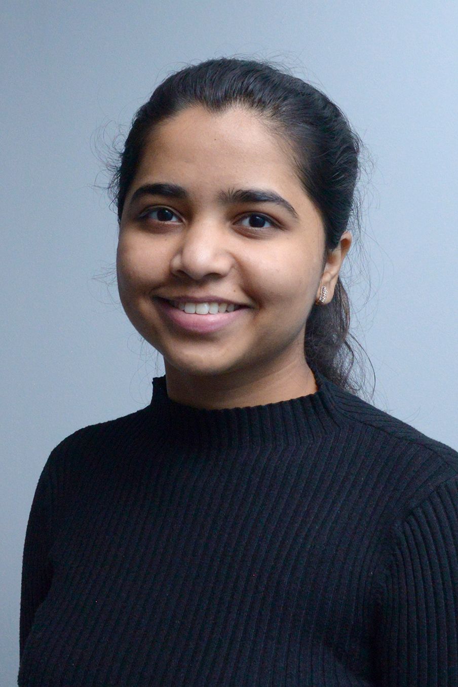 Glasgow corporate portrait of a black-haired indian woman wearing a white top against a light grey background