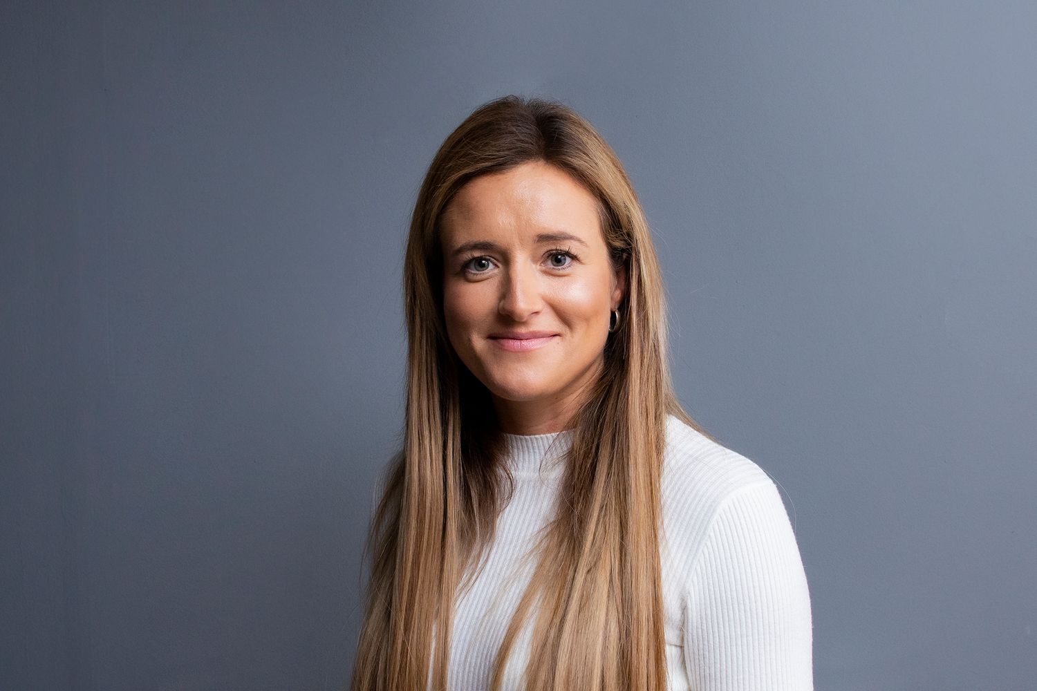 Glasgow corporate headshot of a woman in her thirties with blonde/brown hair and a white top against a grey background