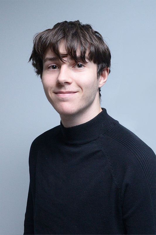 Glasgow corporate portrait of a black-haired young man wearing a black top against a light grey background