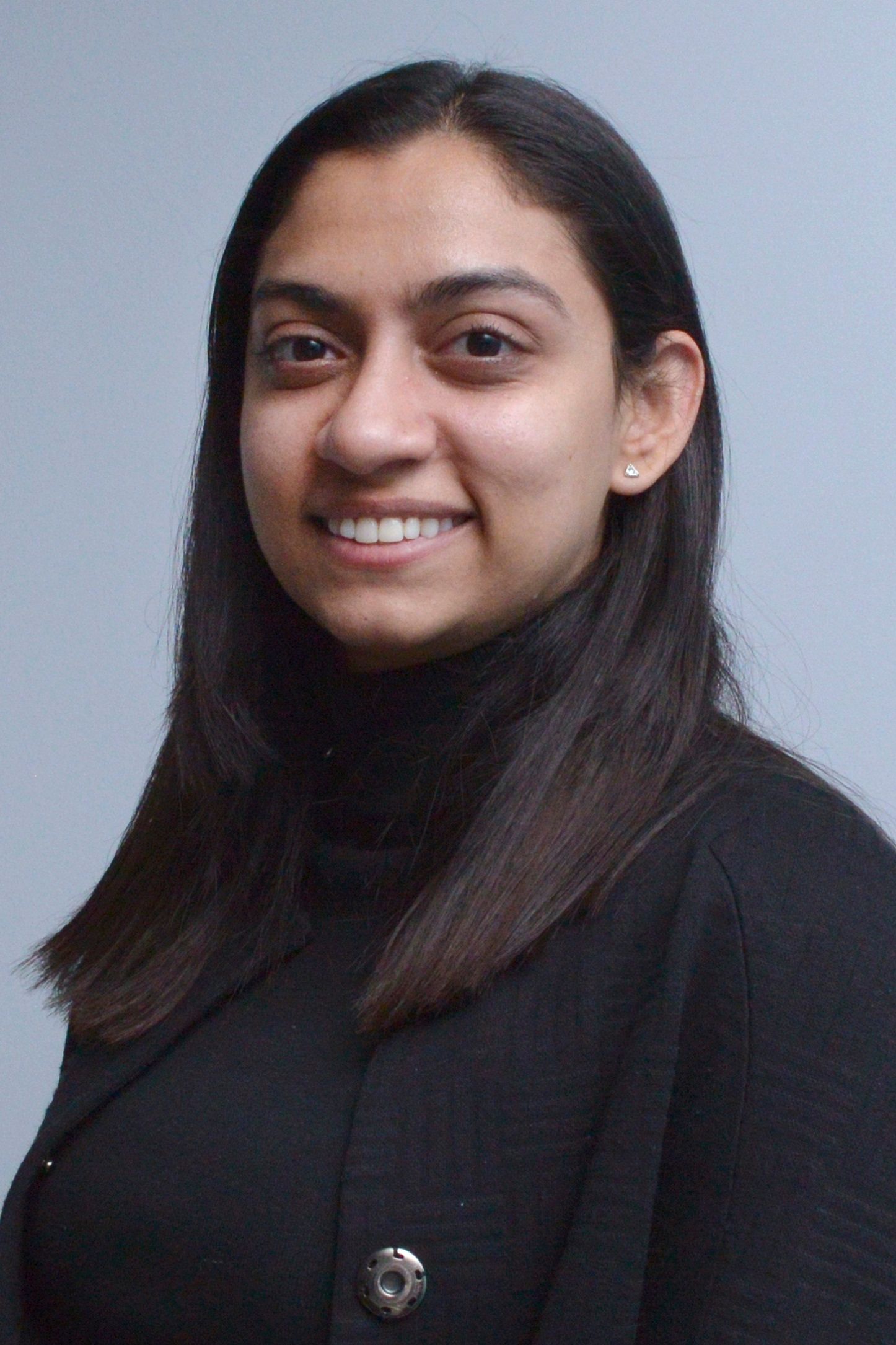 Glasgow corporate portrait of a black-haired indian woman wearing a white top against a light grey background