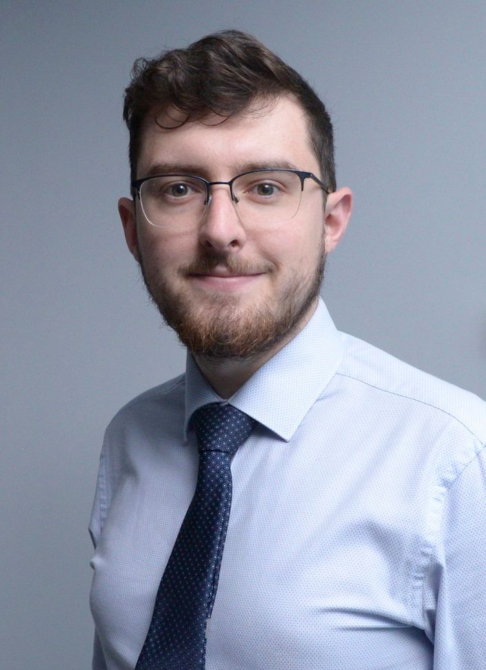 Glasgow corporate portrait of a black-haired young man wearing a light shirt and dark tie against a light grey background