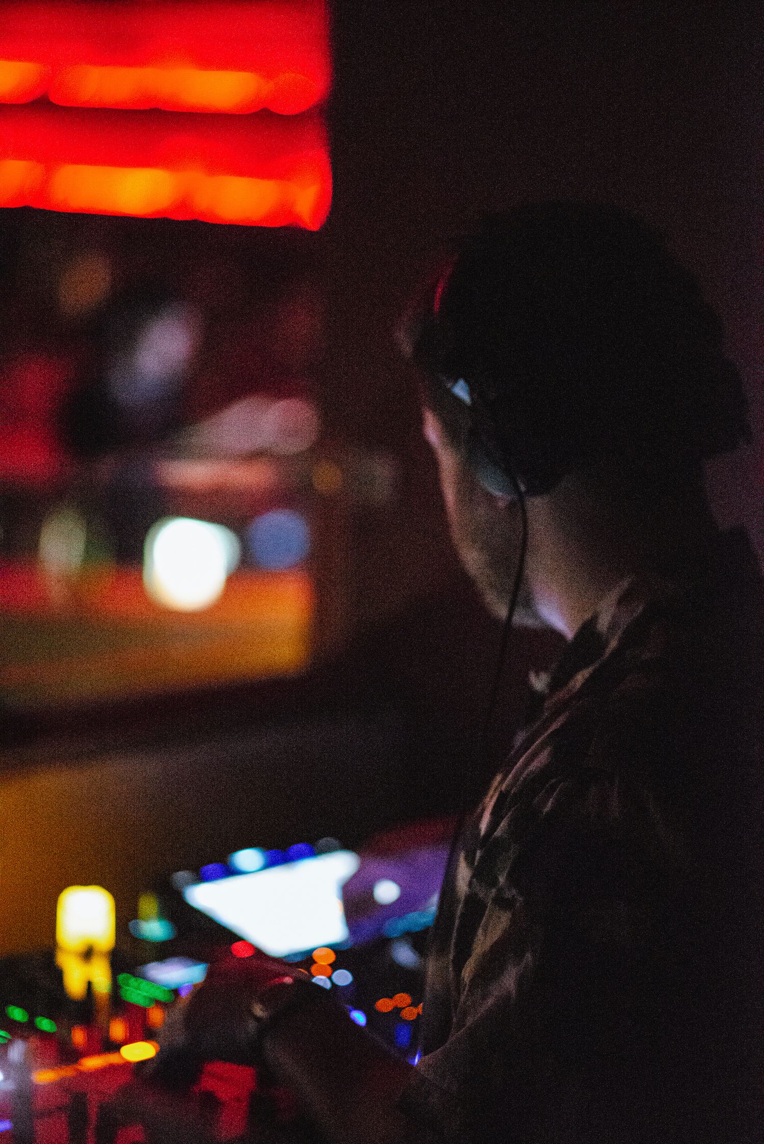 A creative glasgow portrait of a man from behind who is operating a colourful DJ deck in a Glasgow nightclub
