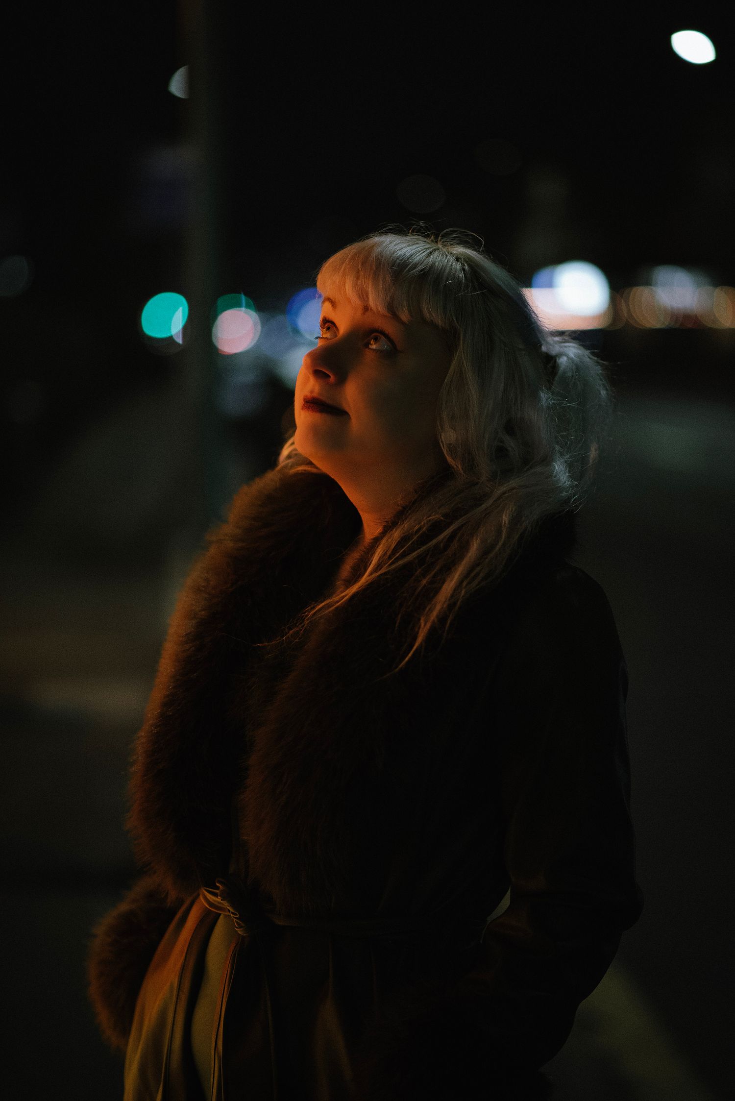 Glasgow creative night time portrait of a woman in her thirties with white hair who is in the street and illuminated with an orange light