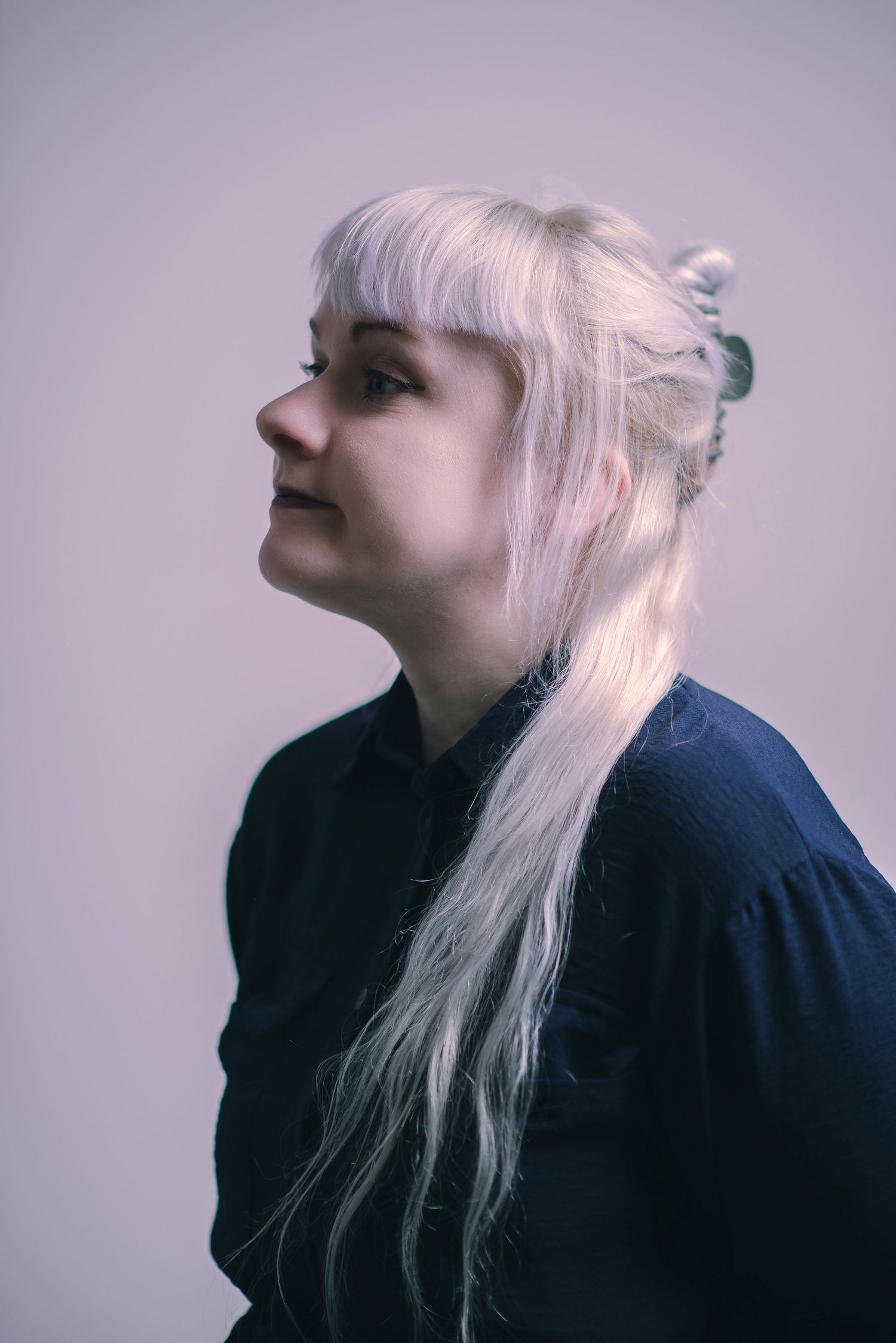 Glasgow corporate headshot of a woman in her thirties with white hair and a dark navy dress against a white background