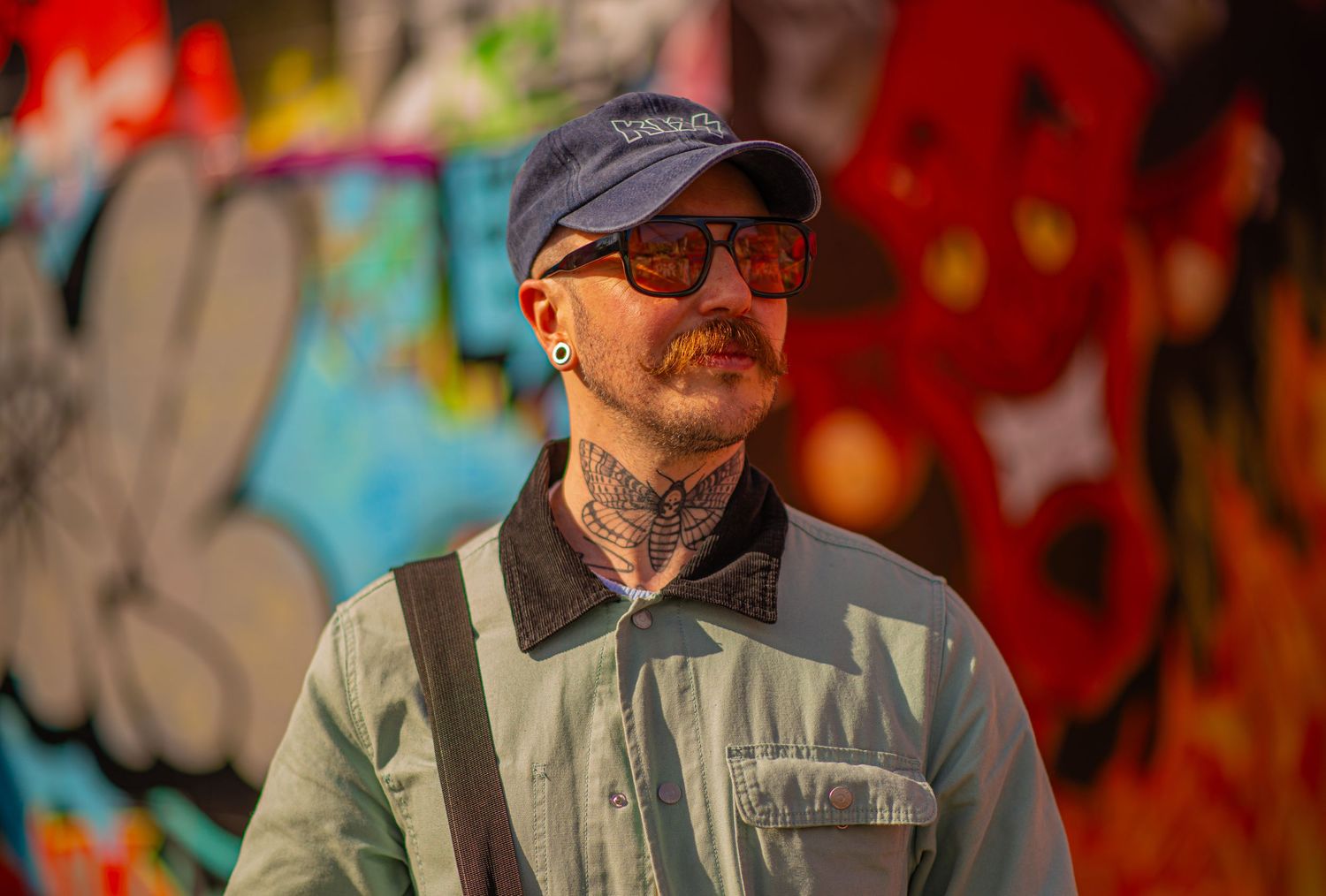 Glasgow creative portrait of a well-dressed man in his thirties standing in front of a wall of colourgful graffiti