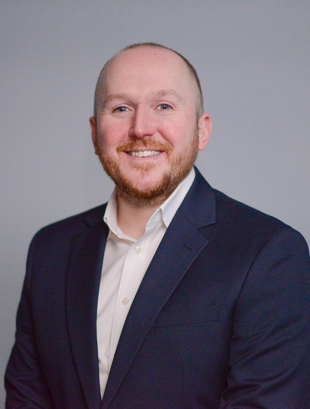 Glasgow corporate headshot of a bald man in his thirties in a dark suit and white shirt against a grey background