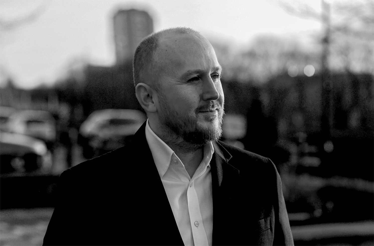 Glasgow corporate black and white outdoor headshot of a bald man in his thirties in a dark suit and white shirt