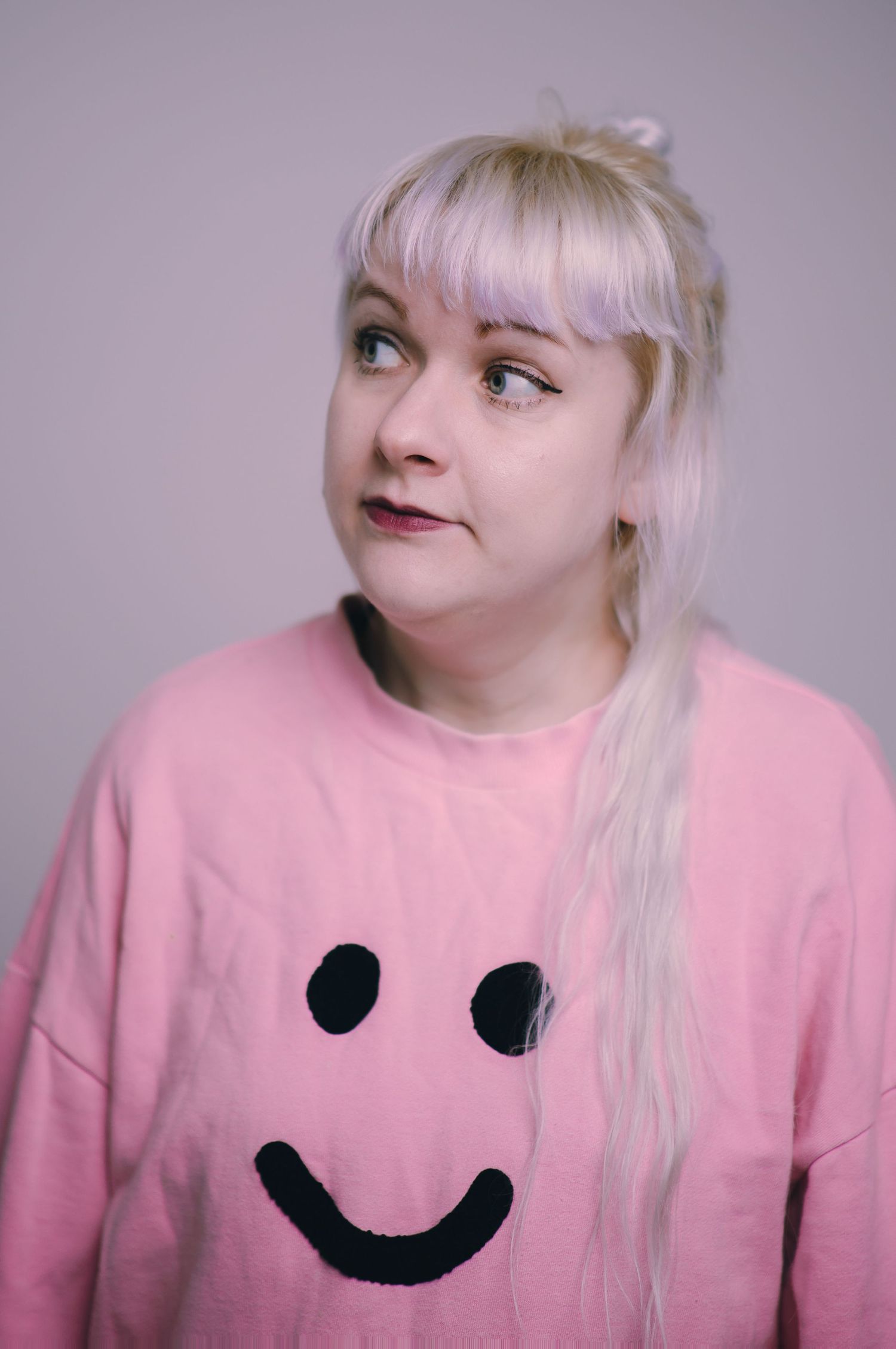 Glasgow headshot of a woman in her thirties with white hair and a pink jumper against a white background