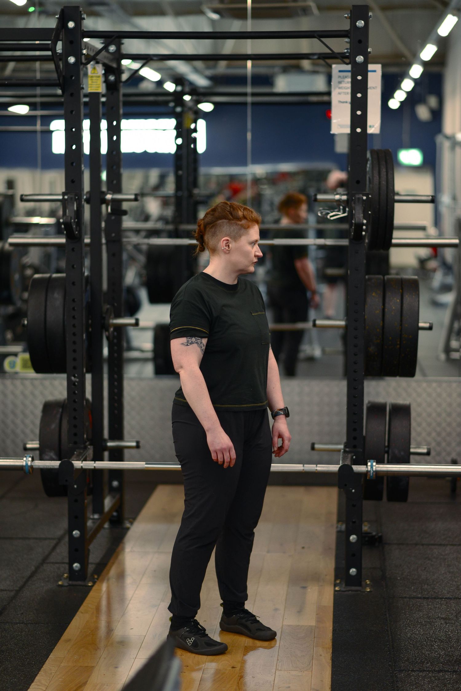 Glasgow portrait of a red-haired woman in a gym, wearing all black in a barbell lifting area