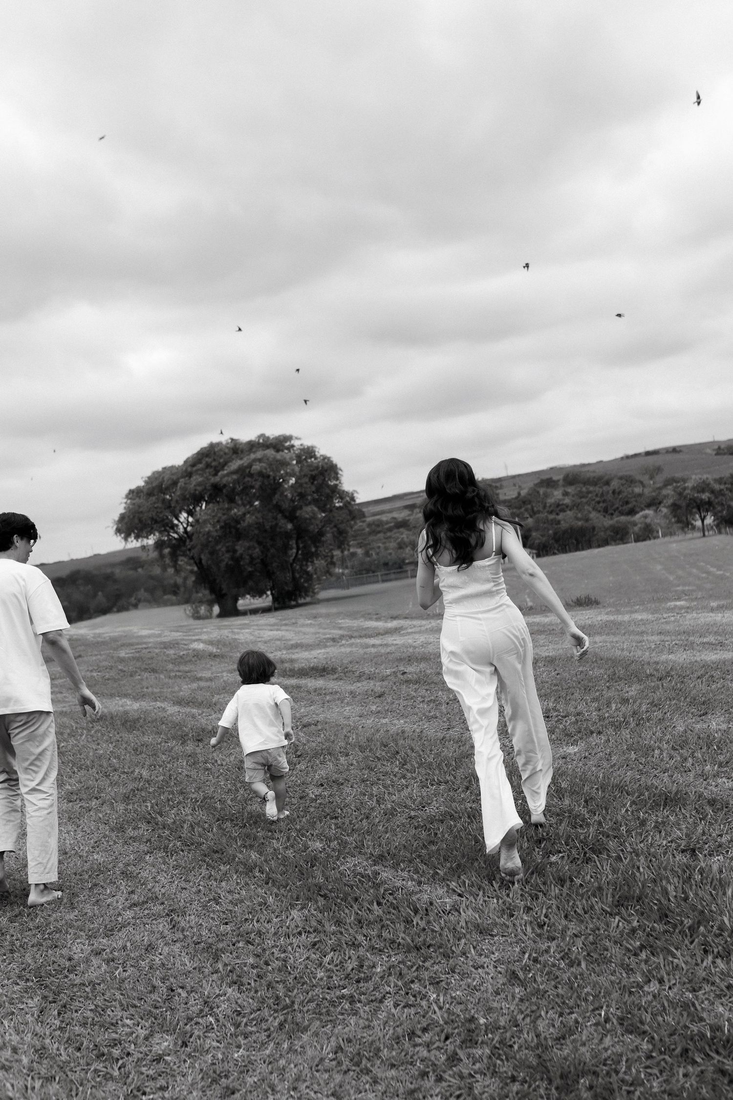 People in white clothing running across a grassy field on an overcast day.