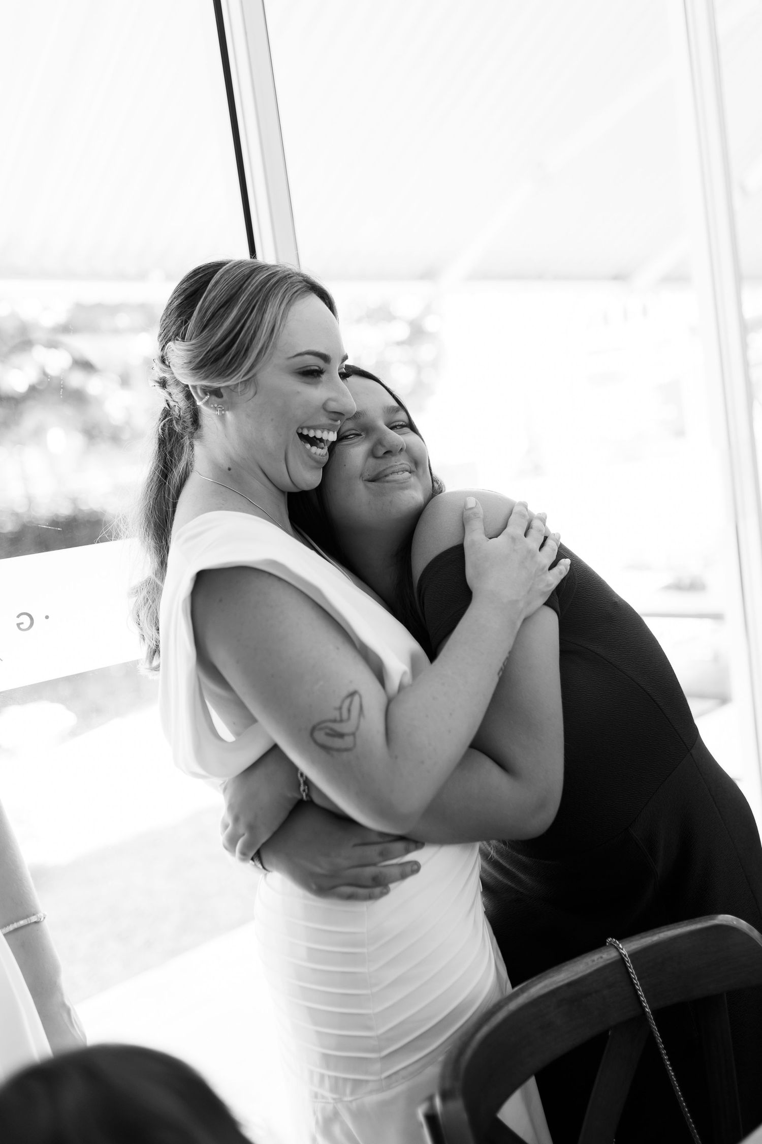 Two people in formal attire sharing emotional embraces in a bright indoor setting.