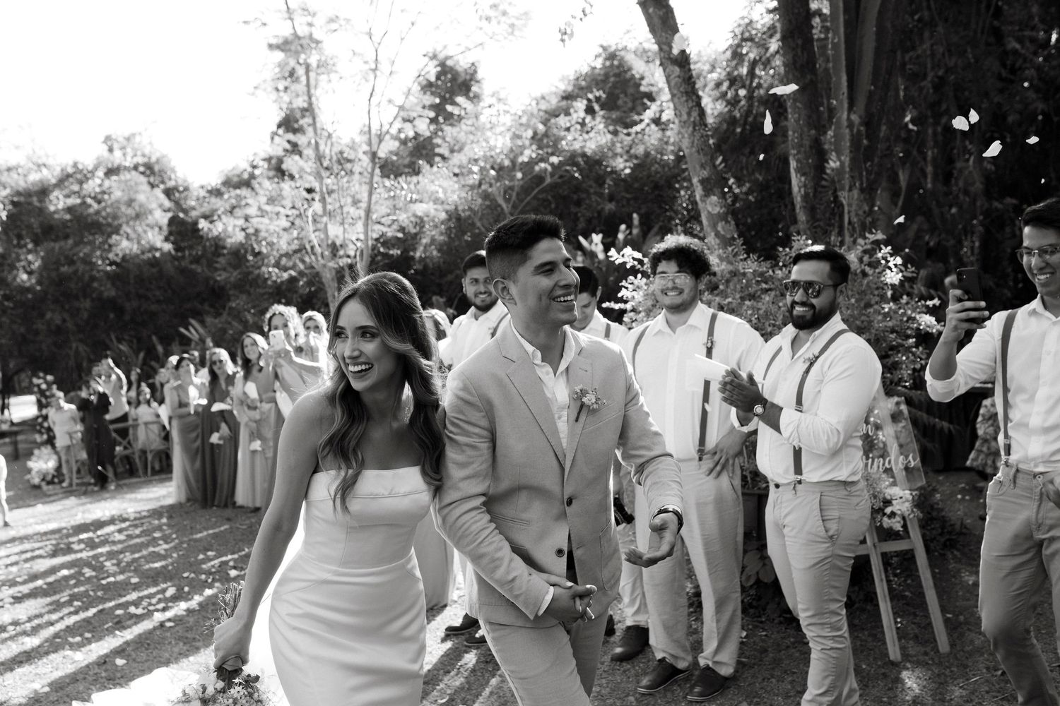 Wedding party walks together outdoors wearing coordinated white and beige attire.
