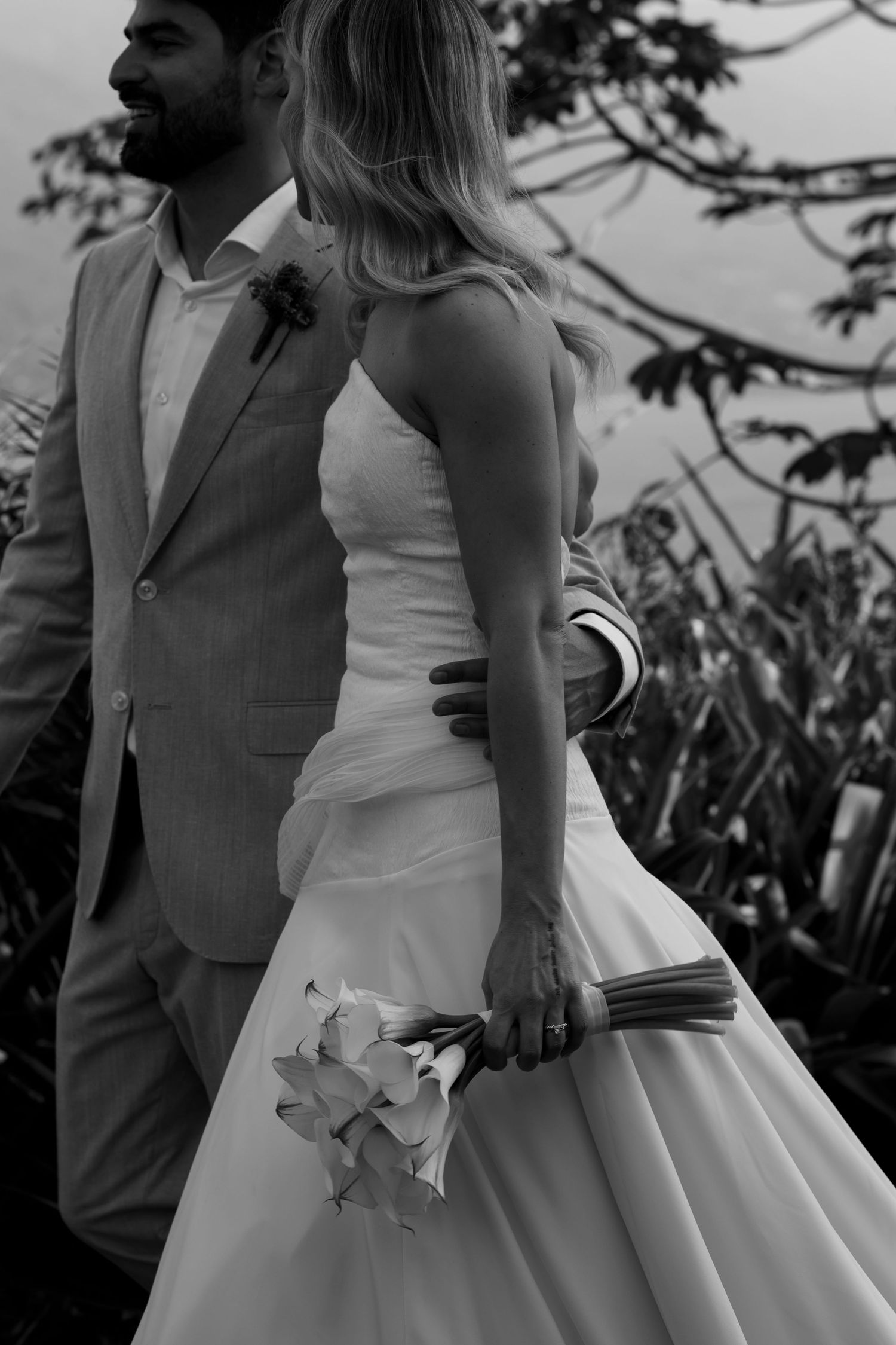 A wedding couple stands together in formal attire with a white ballgown dress and gray suit.