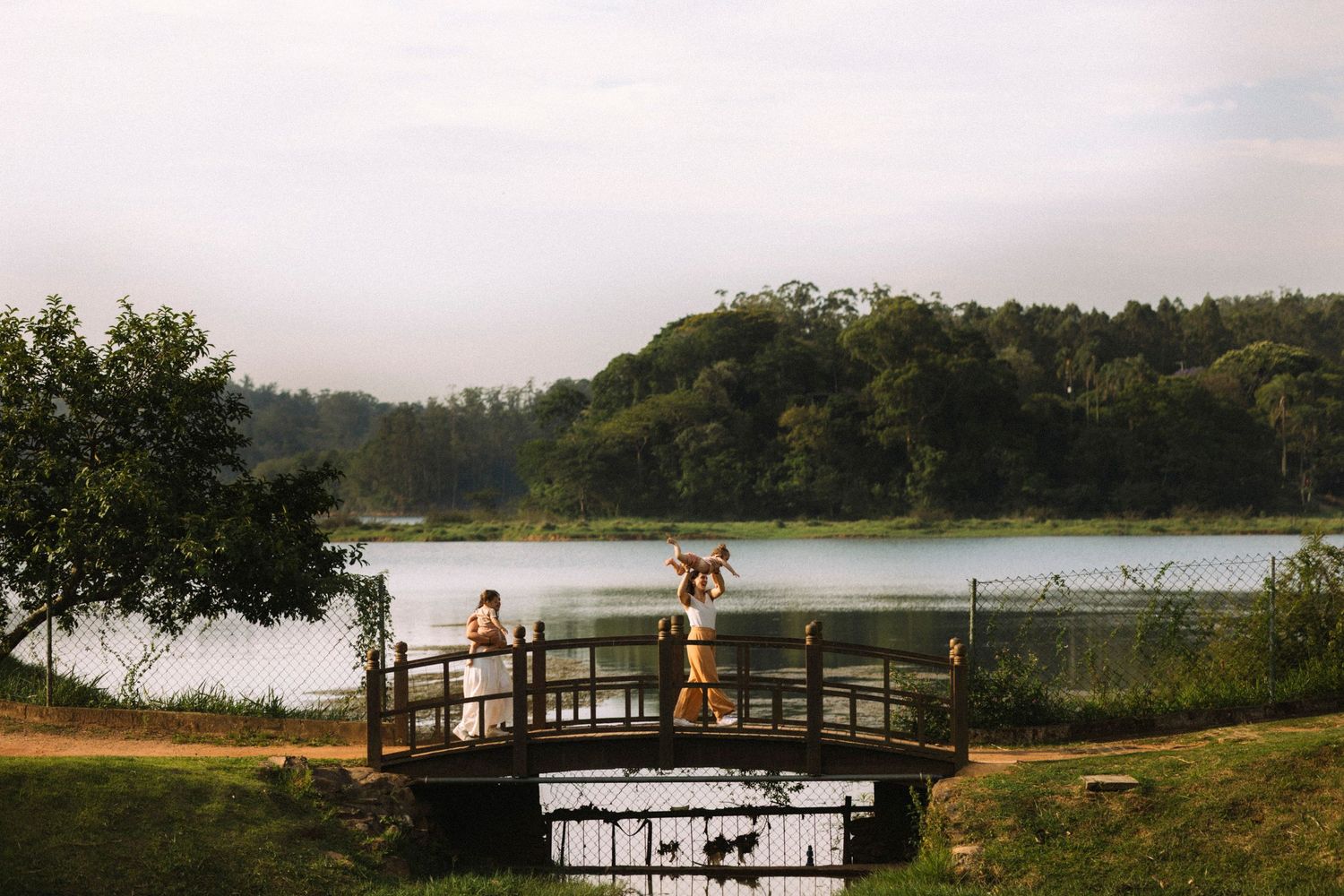 Scenic lakeside boardwalk stretching across calm waters during golden hour.