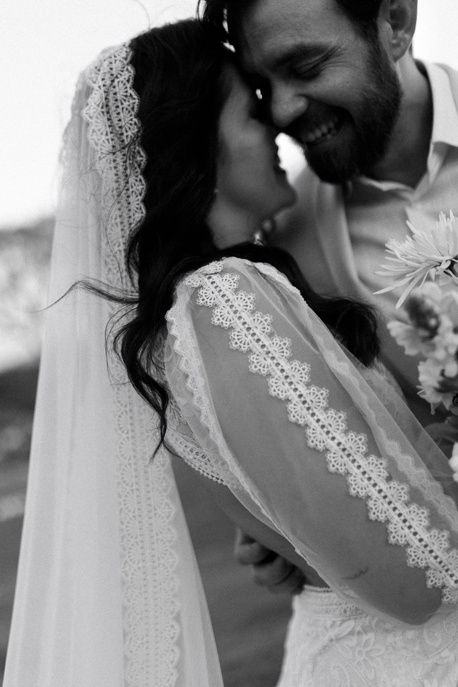 Intimate black and white portrait of newlyweds with lace veil details.