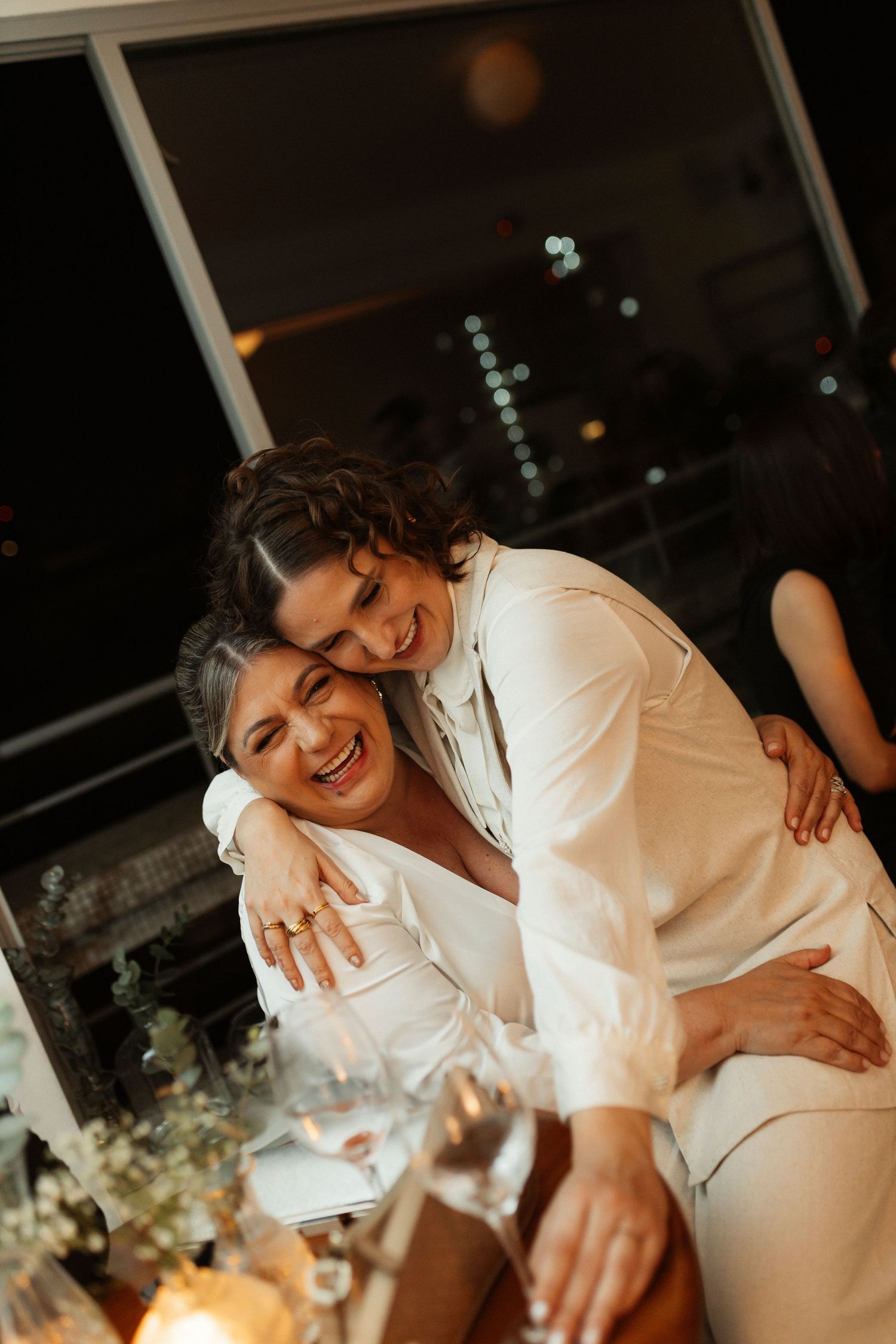 A joyful celebration moment captured in warm lighting with white outfits and genuine laughter.
