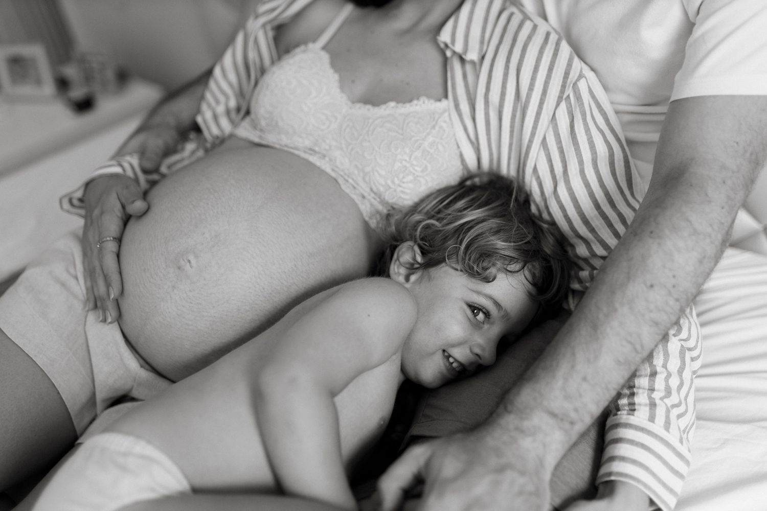 Intimate black and white maternity photo showing tender family moment.