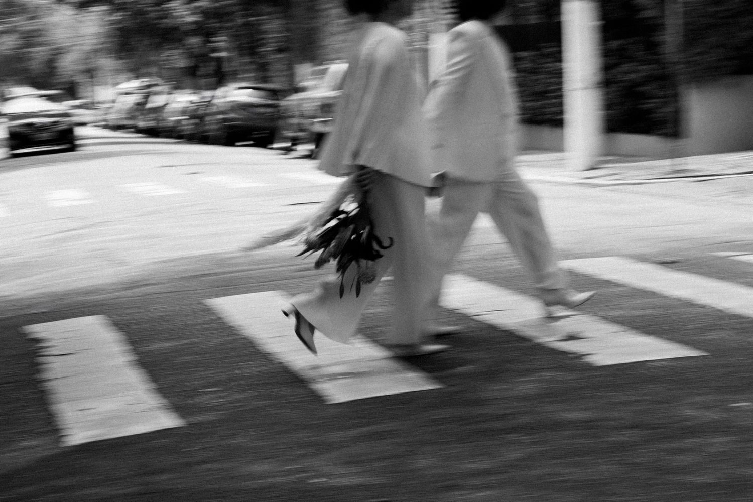 Motion-blurred black and white image of people walking on a street.