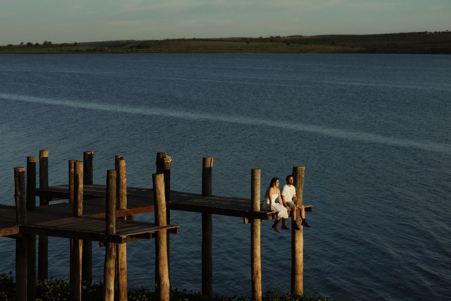Peaceful waterfront scene with wooden dock extending into calm waters at dusk.