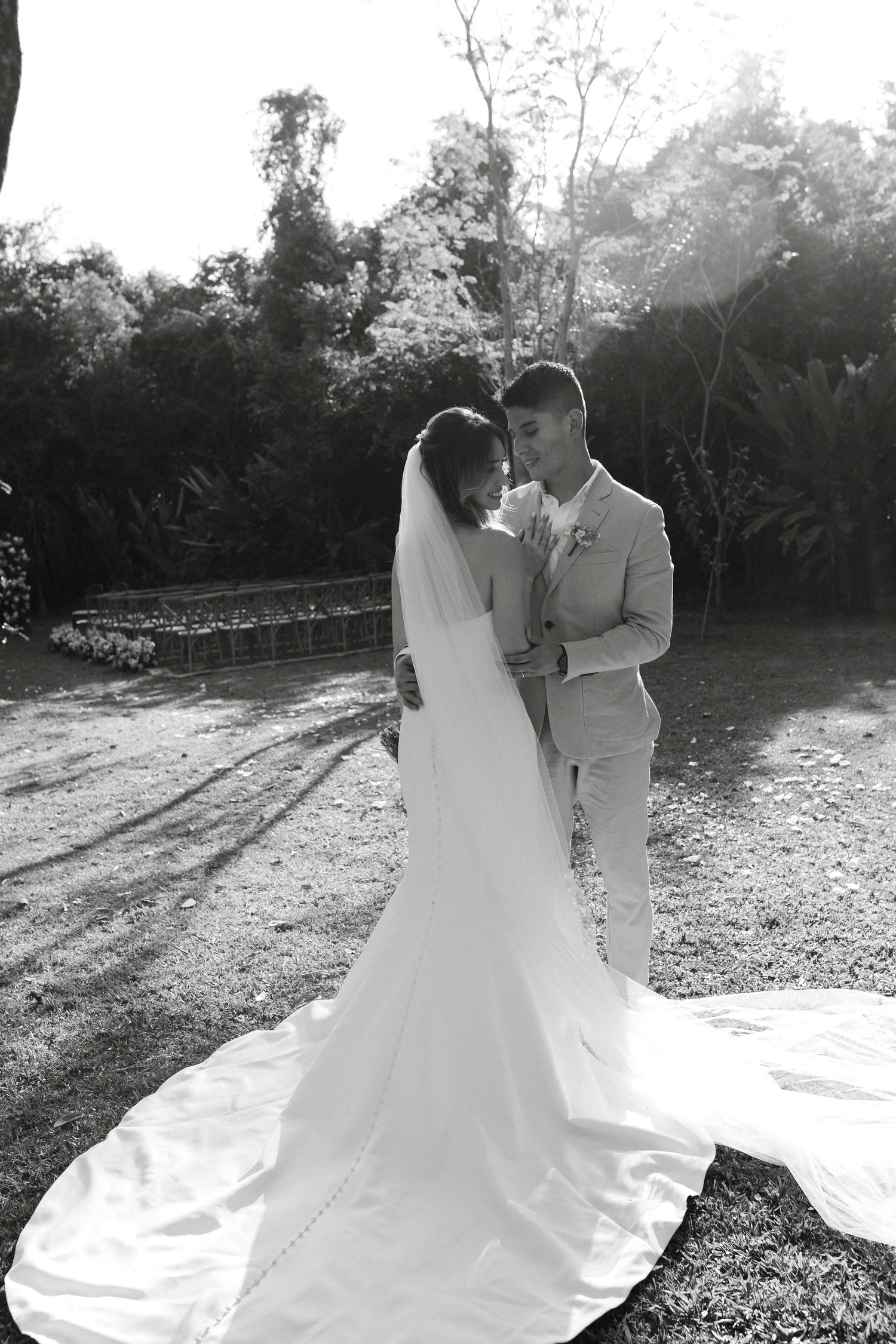 A bride's white wedding dress train spreads beautifully across the ground during an outdoor photo session.