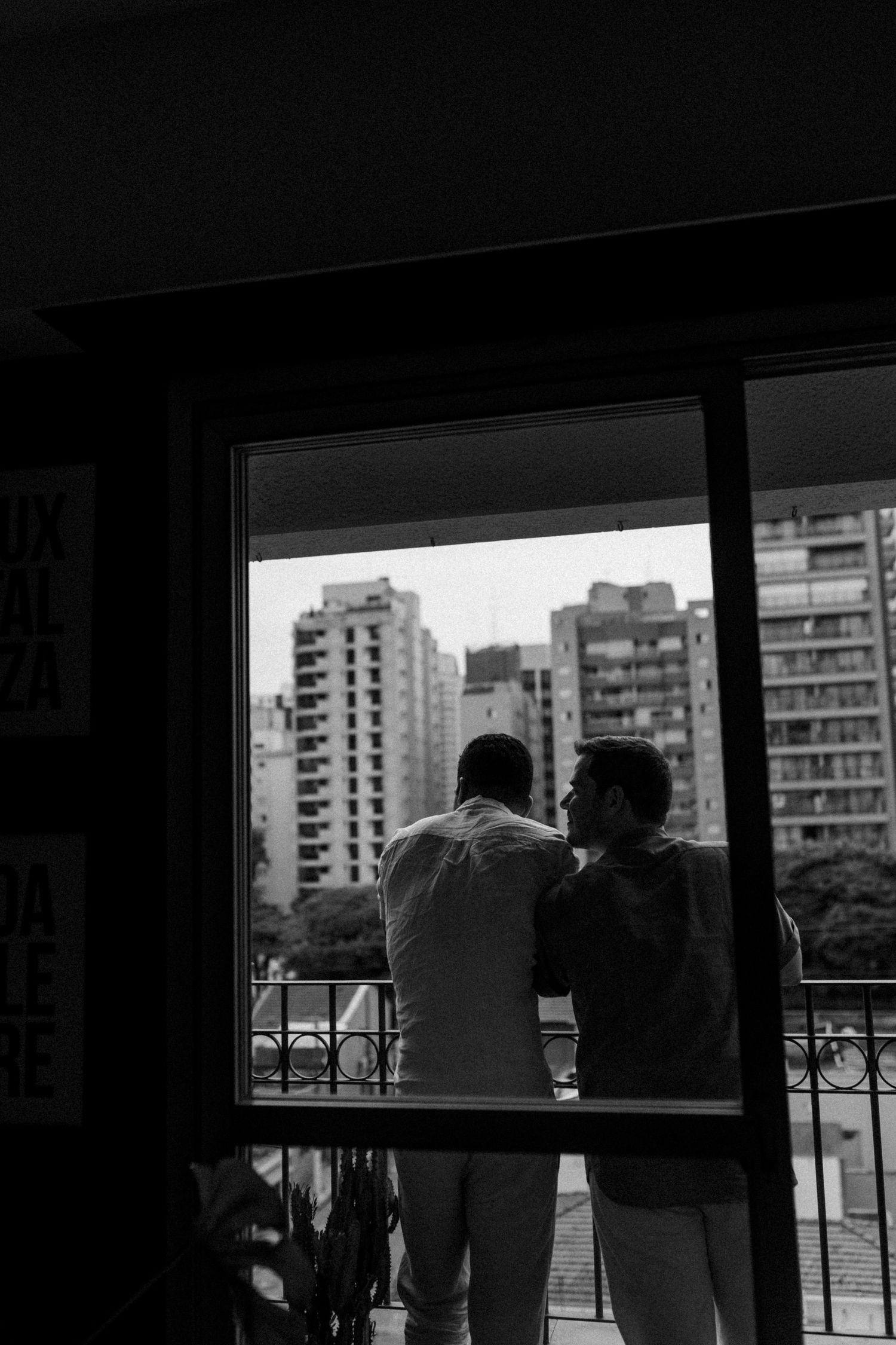Silhouettes against bright windows overlooking city buildings.