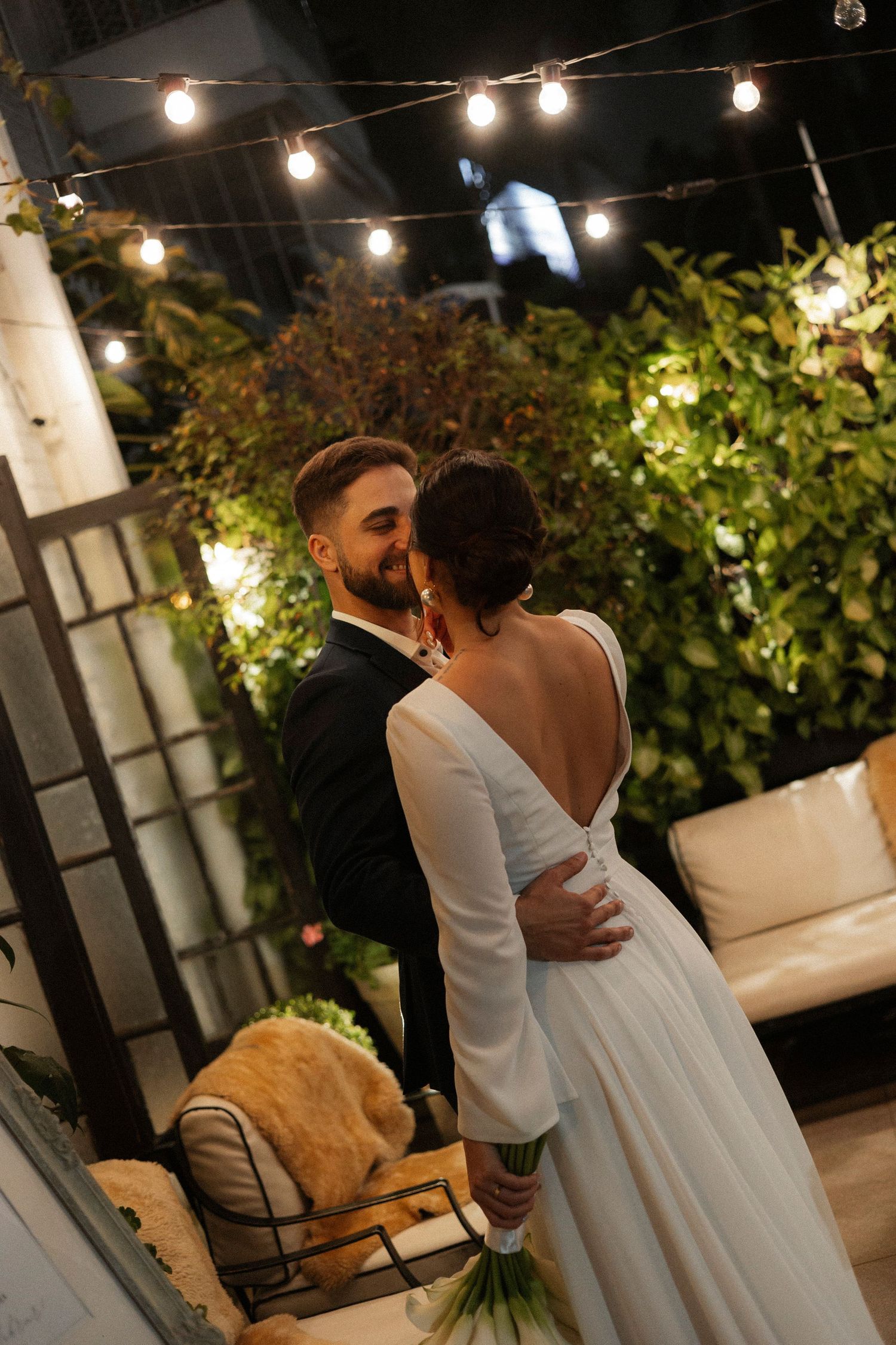 Evening wedding reception under string lights with greenery and romantic ambiance.