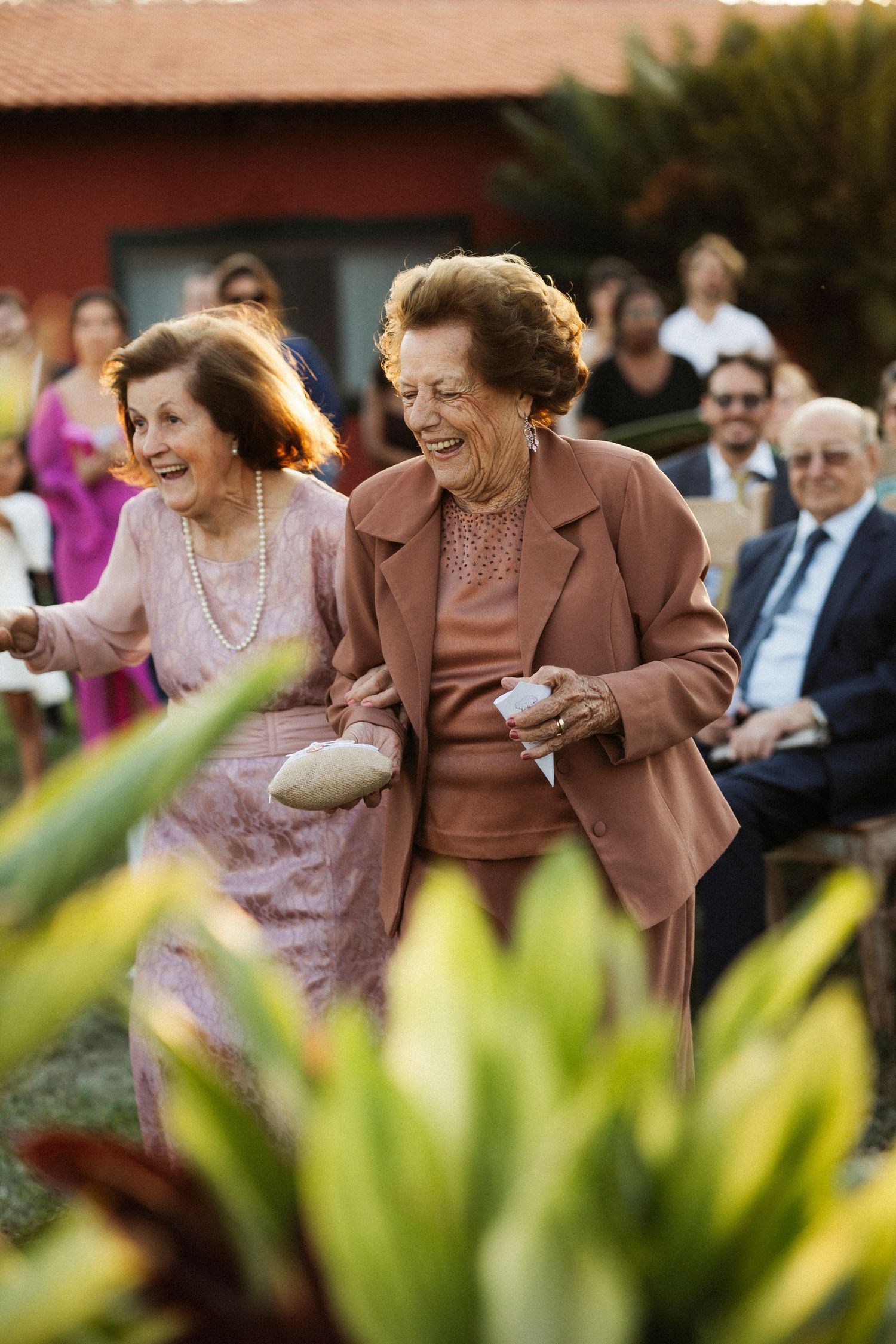 Wedding guests share joyful laughter during an outdoor celebration.