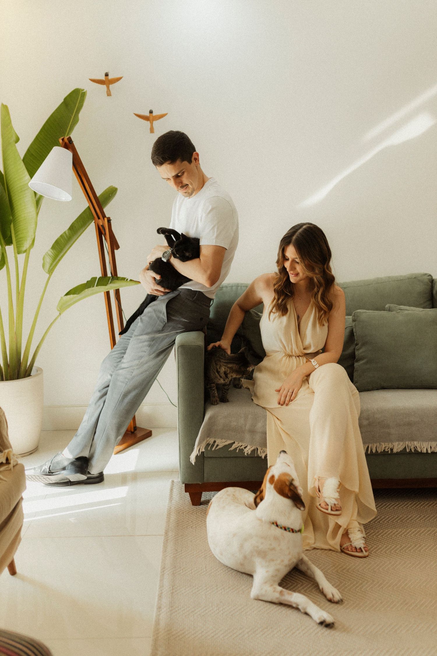 Couple relaxing on grey couch with indoor plants in modern minimalist setting.