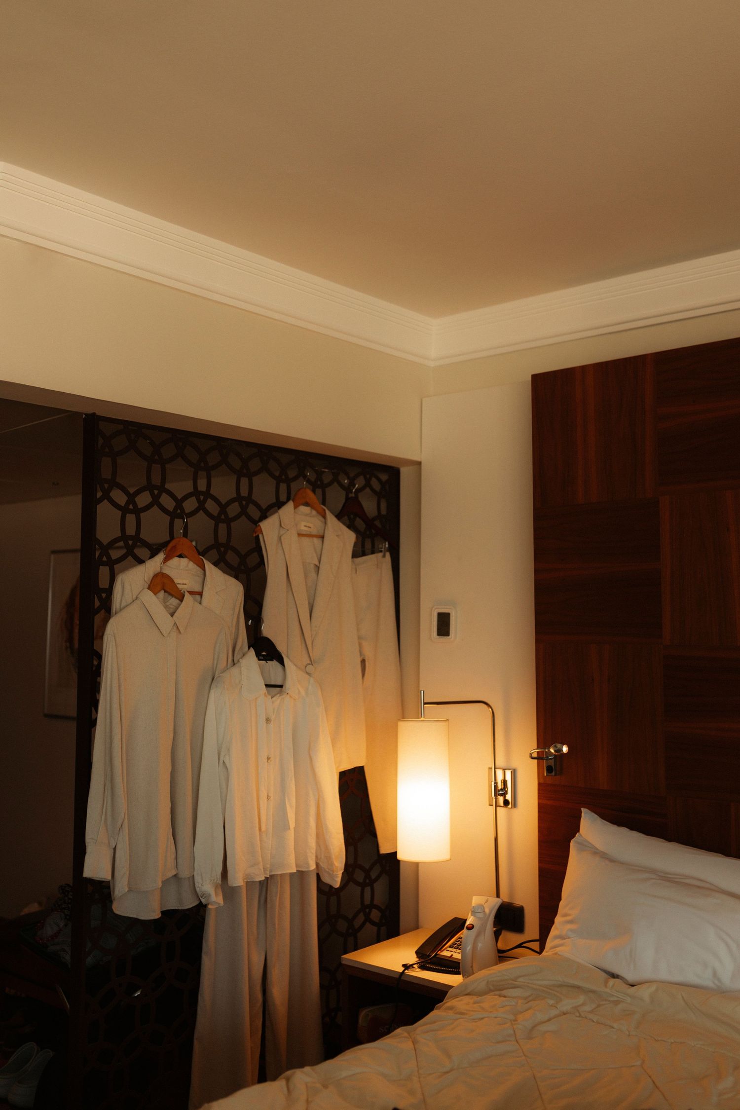White shirts hanging in a warmly lit hotel room with modern decor.