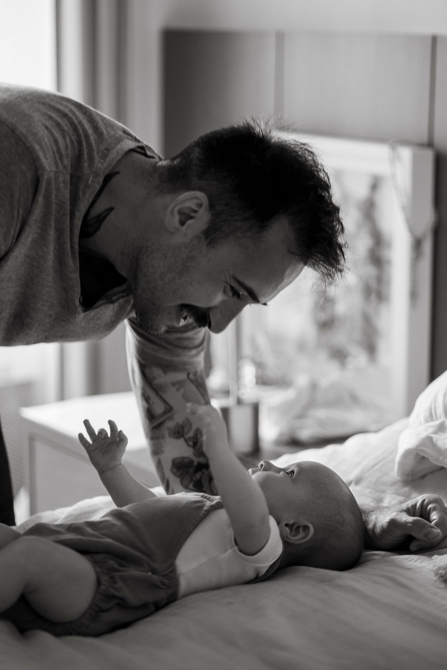 Black and white sequence showing tender moments between parent and baby on a bed.