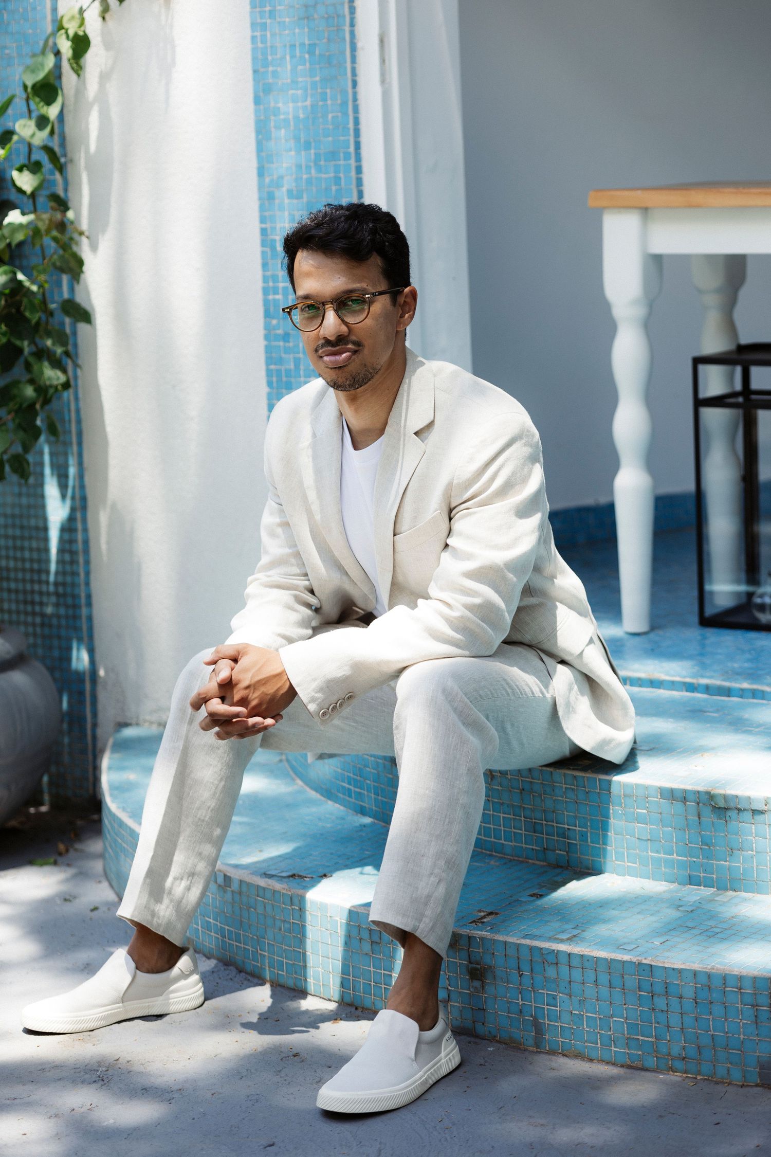 Person in white attire sitting on blue tiled steps in contemplative poses.