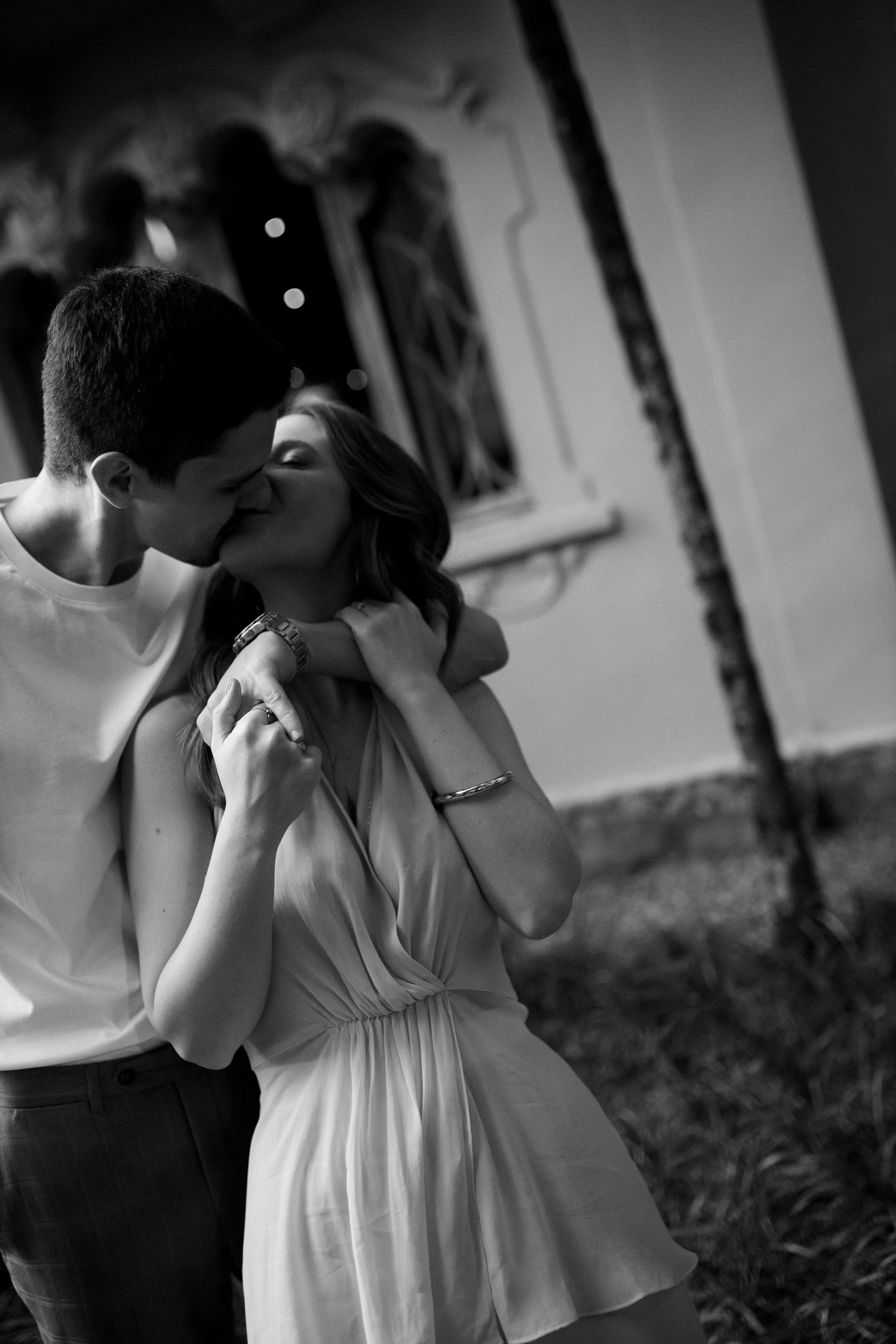 Intimate black and white photo of couple sharing tender moment outdoors.
