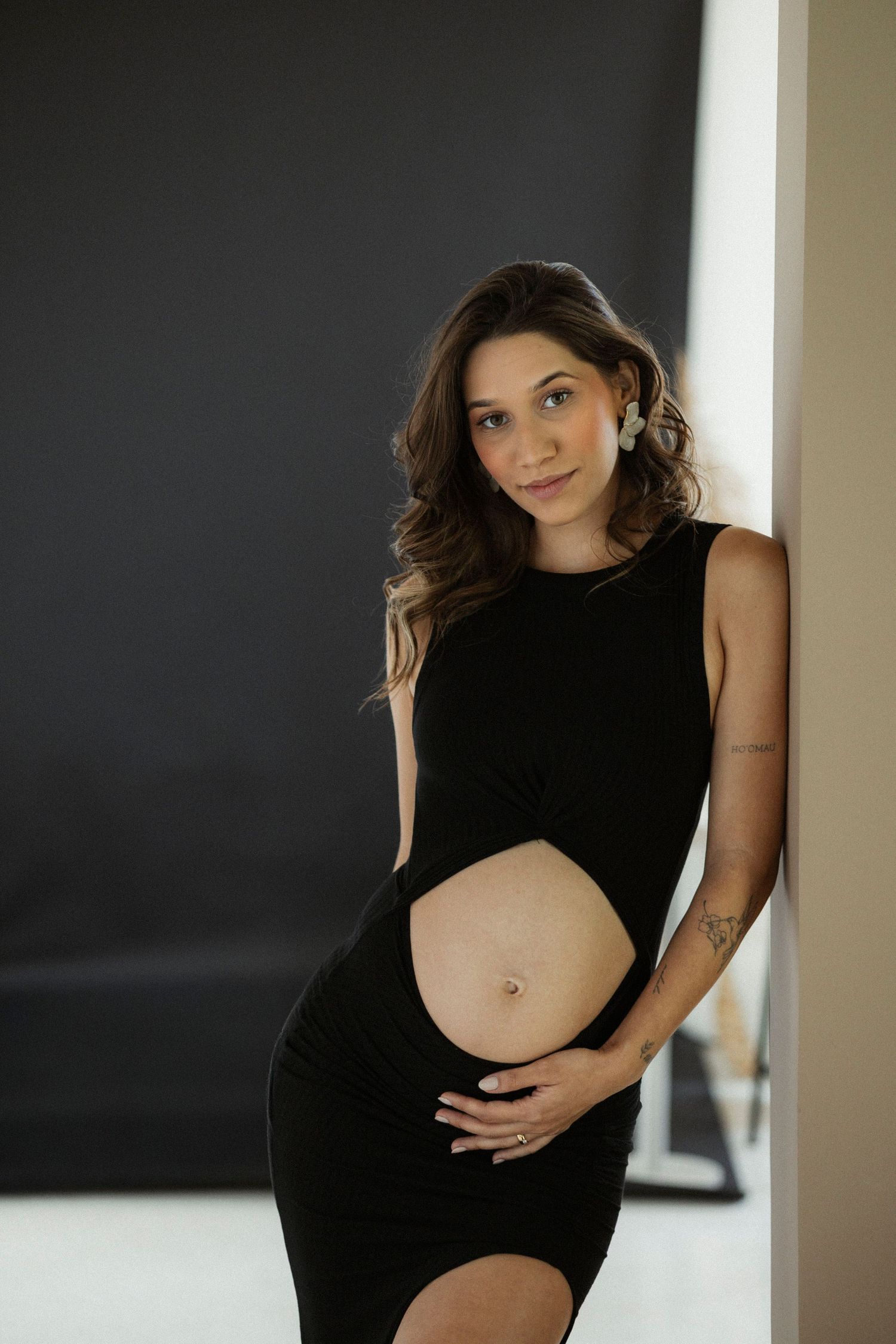A series of artistic maternity portraits showing a woman in a black dress against neutral backgrounds.